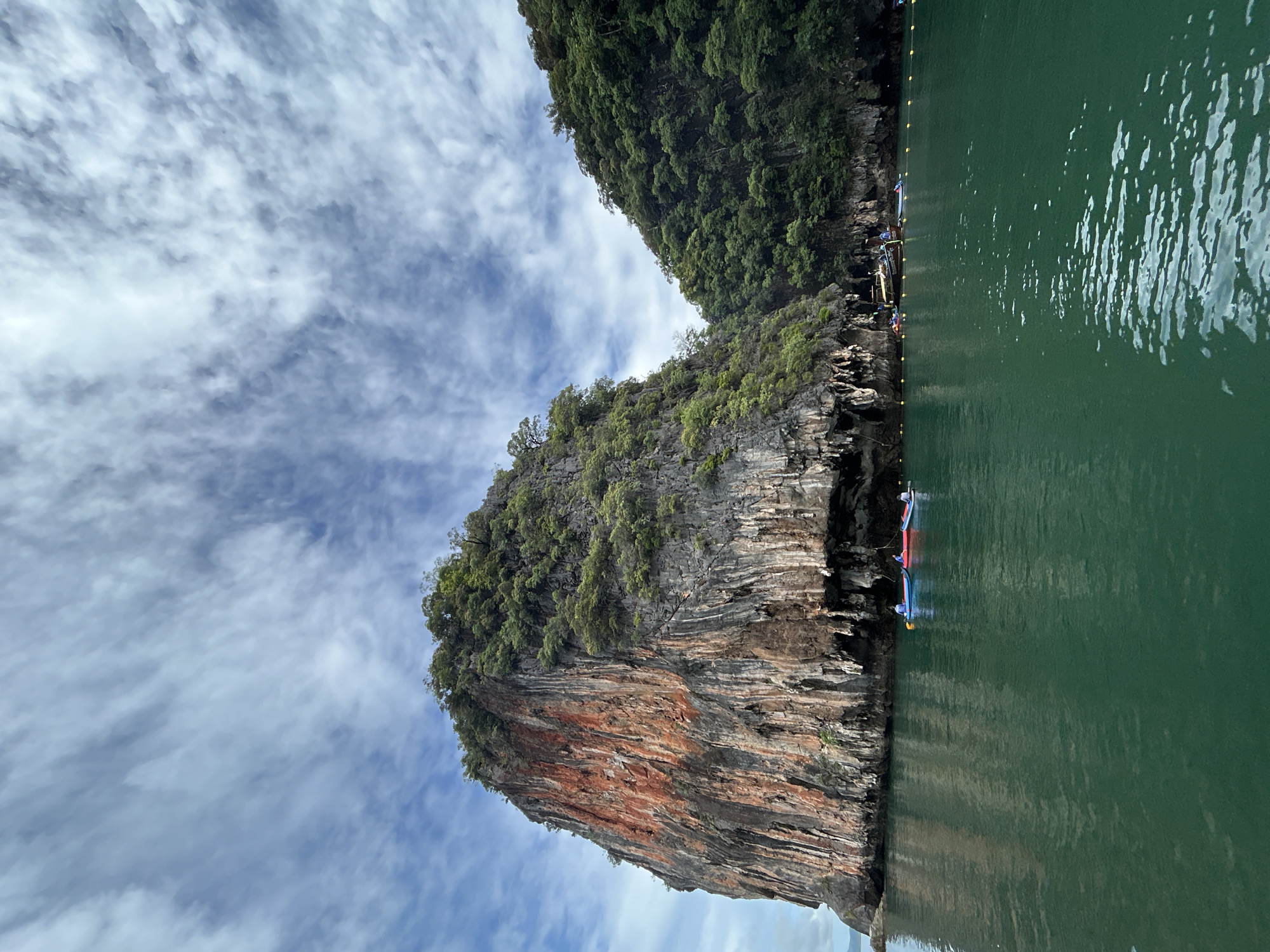 Rugged limestone island cliff rising from green Andaman waters