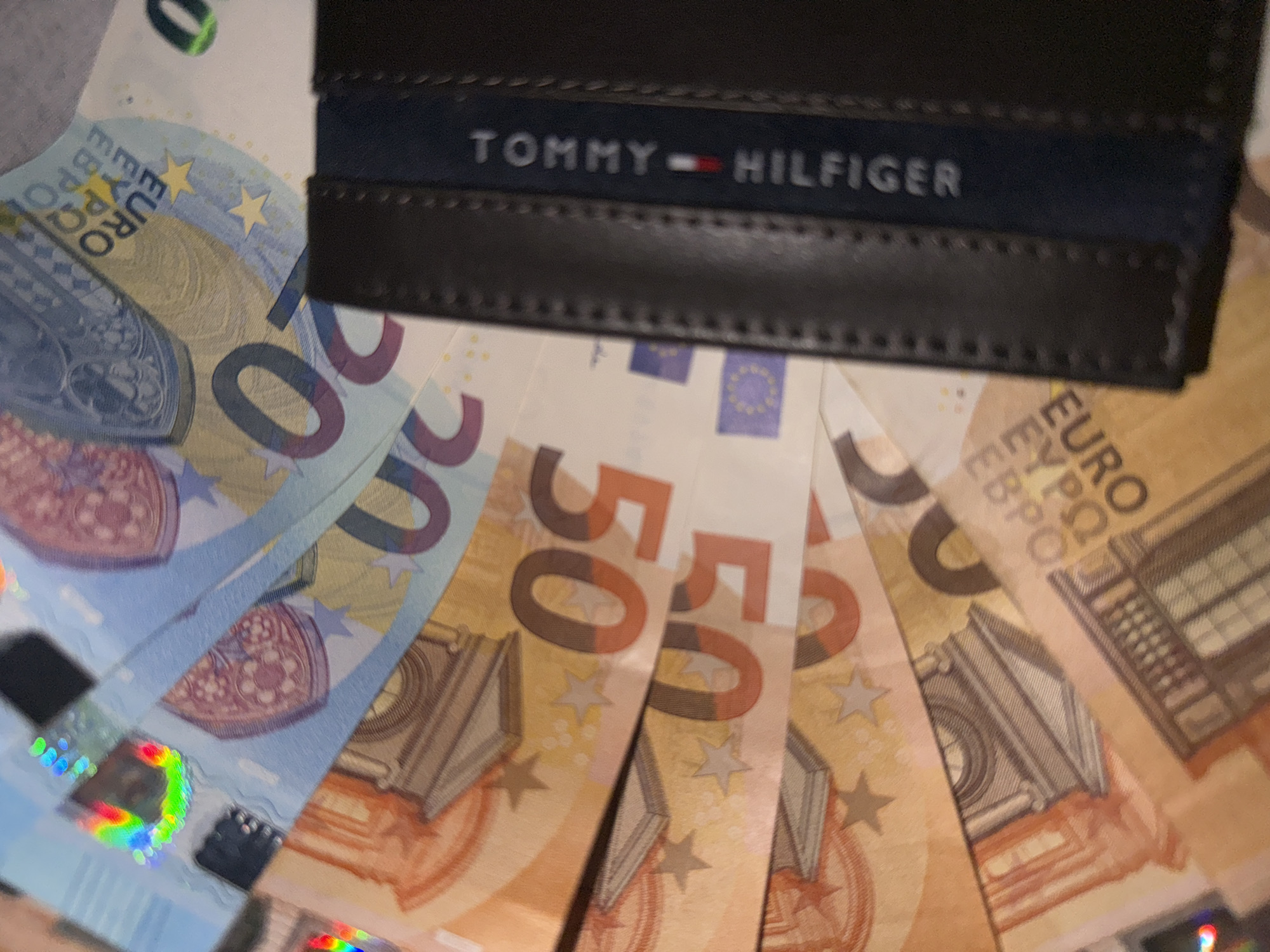 Tommy Hilfiger wallet photographed with scattered Euro banknotes