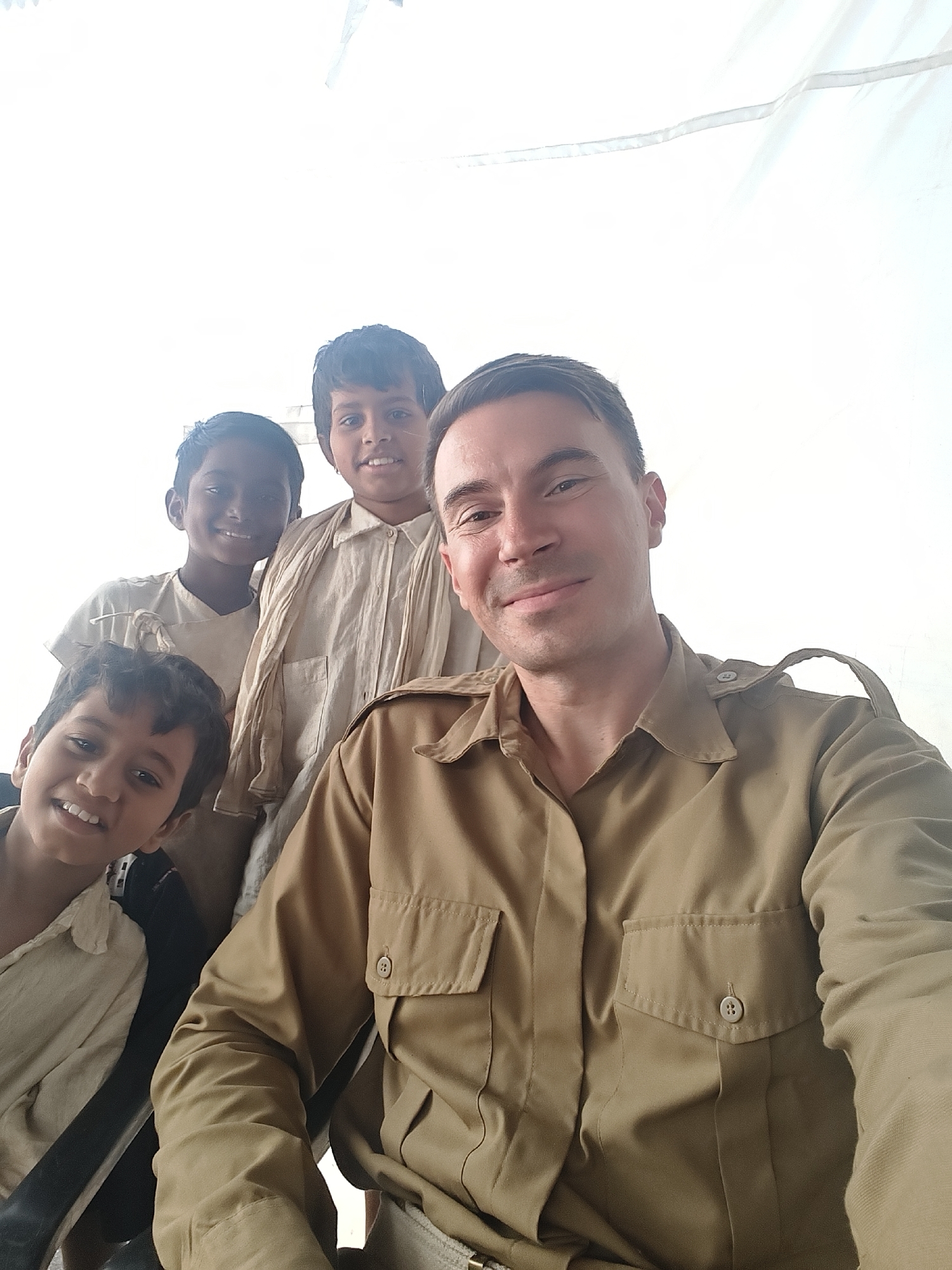 Man in safari gear photographed with children during gathering