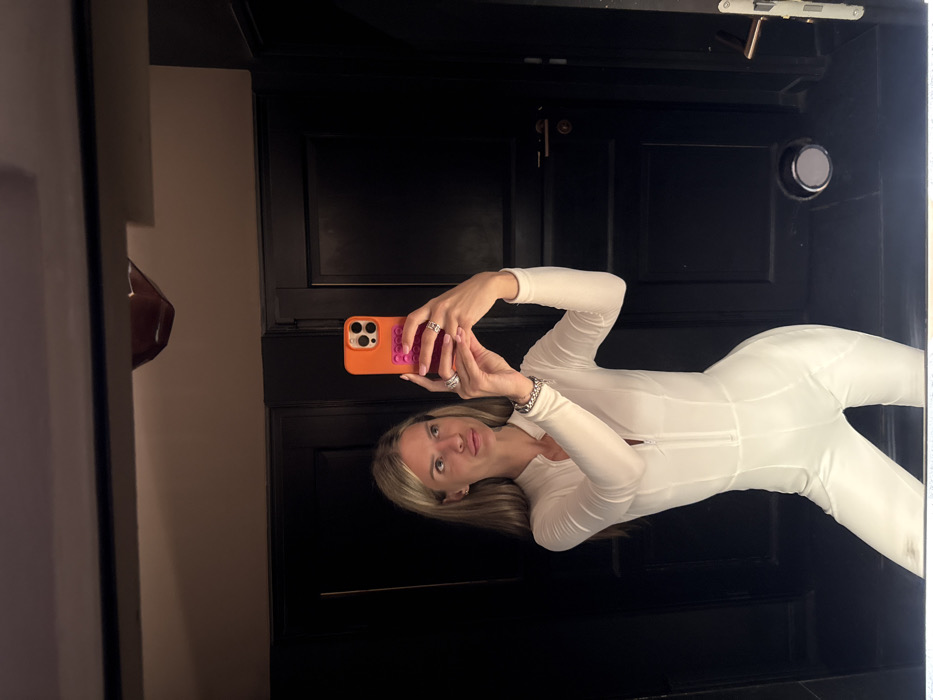 Woman takes mirror selfie in white jumpsuit in Berlin