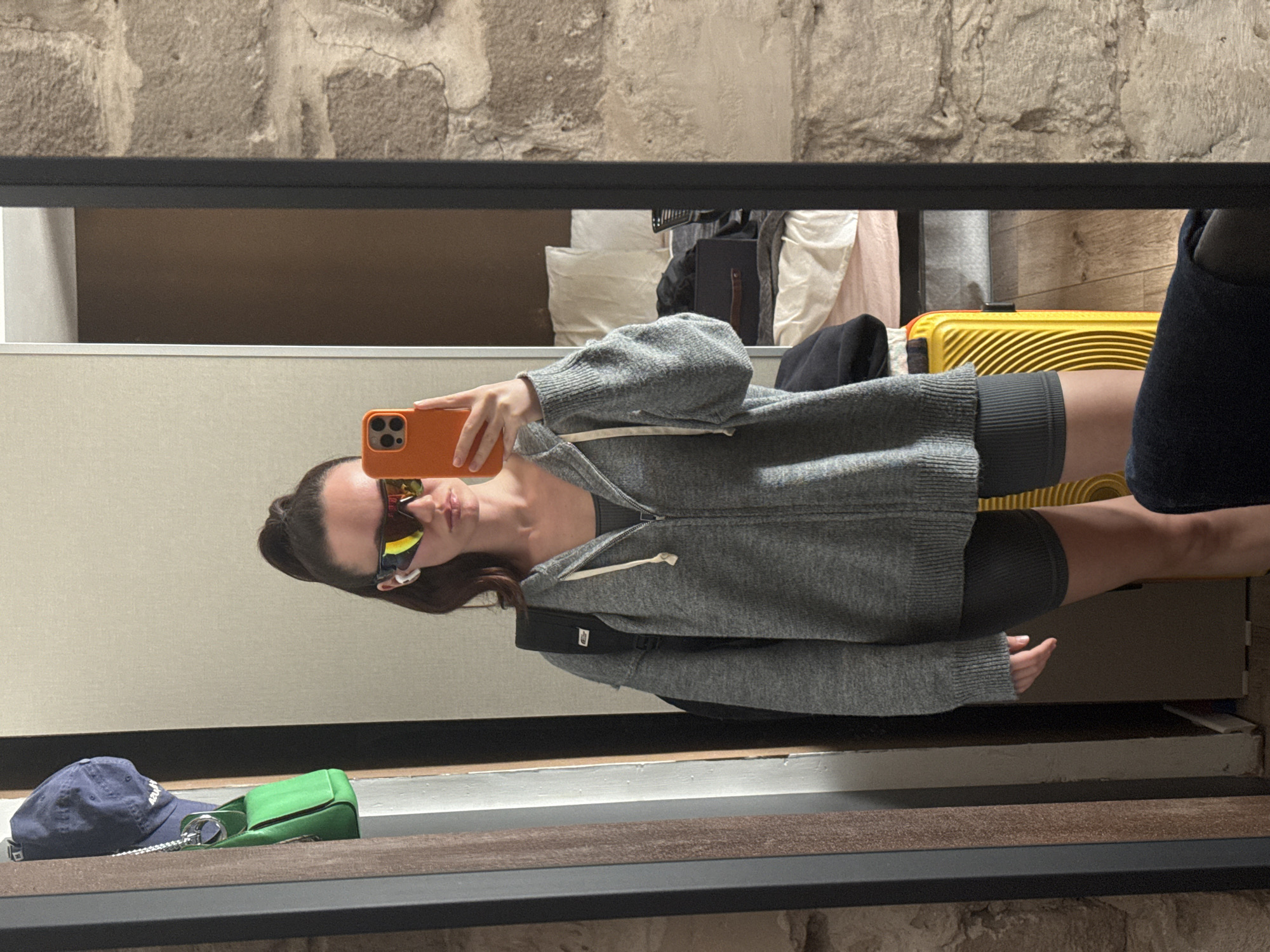 Woman photographed in mirror reflection holding orange phone in Tel Aviv
