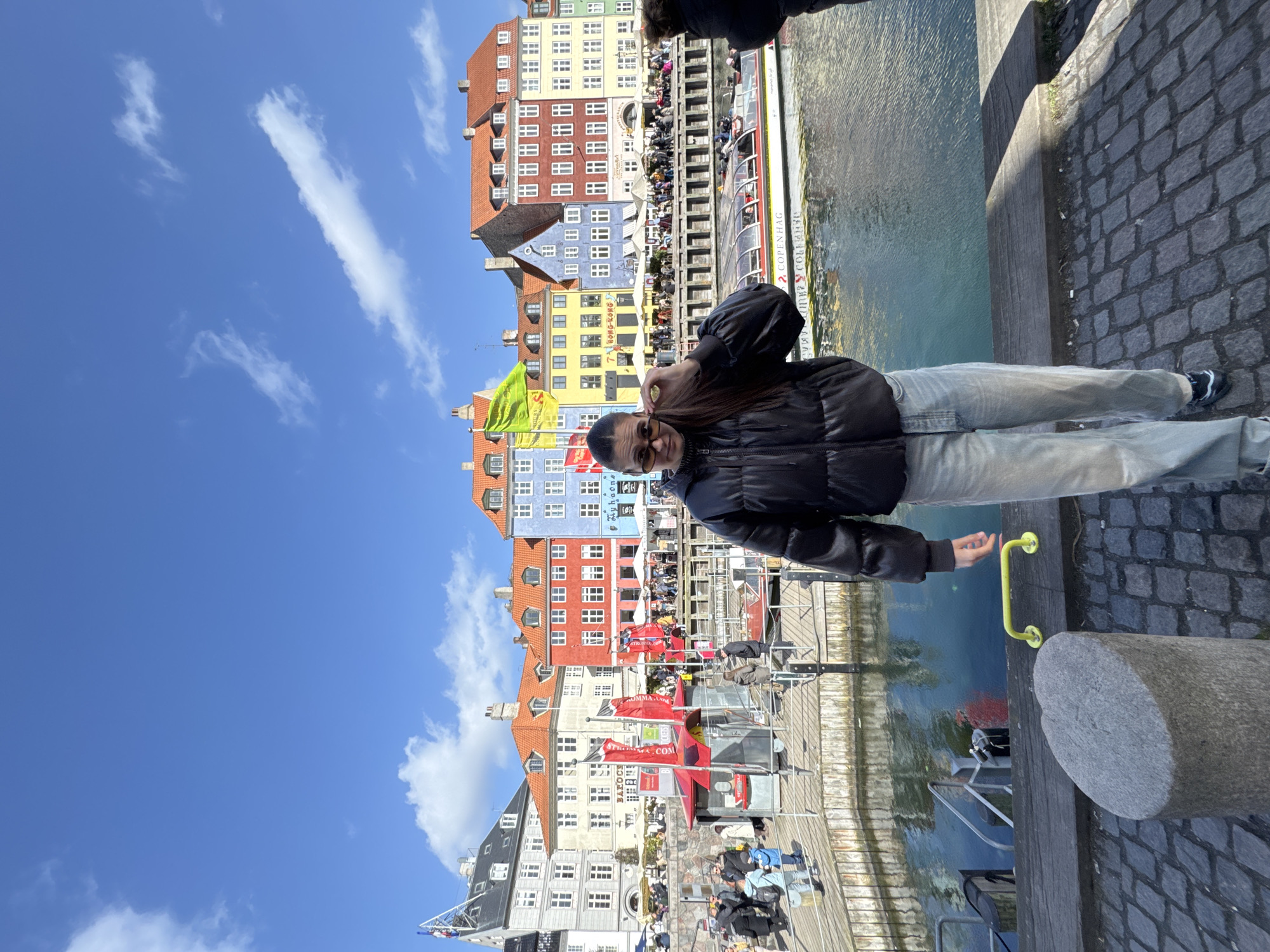 Tourists gather at sunny Nyhavn harbor in Copenhagen