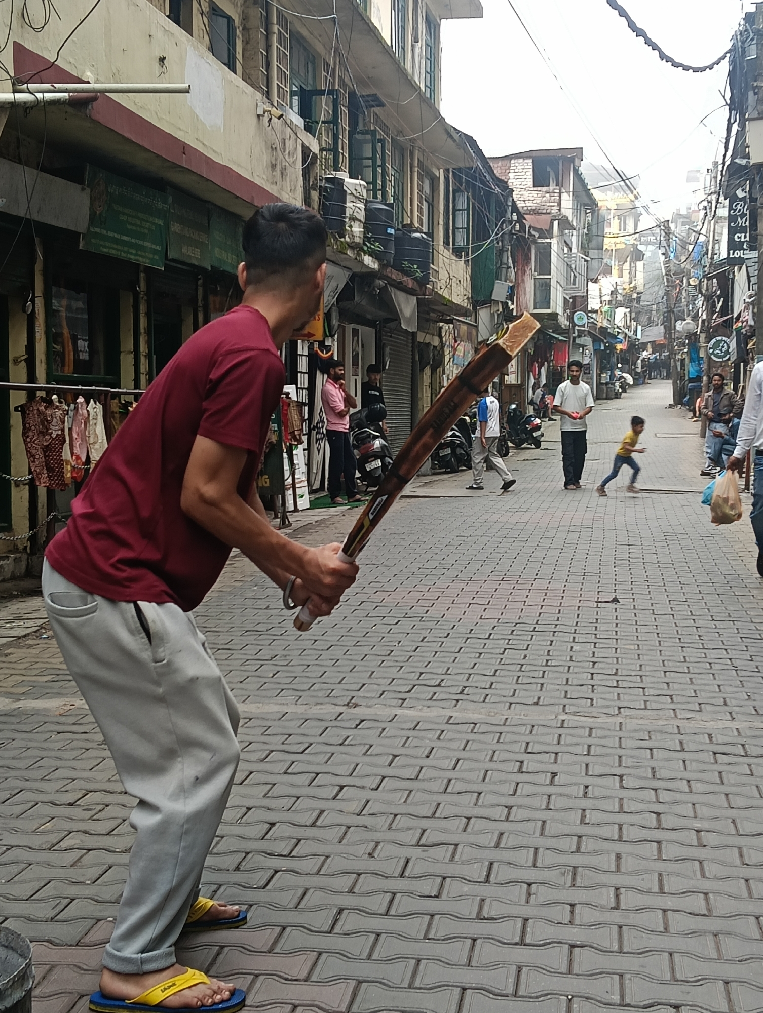 Street cricket in a Dharamshala lane, bat in hand