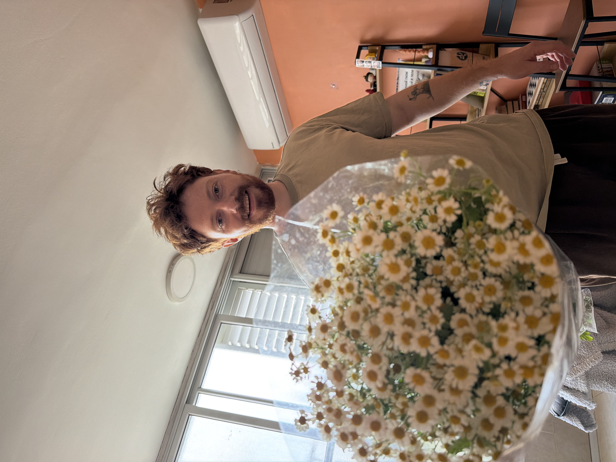 Man holds daisy bouquet indoors in Tel Aviv