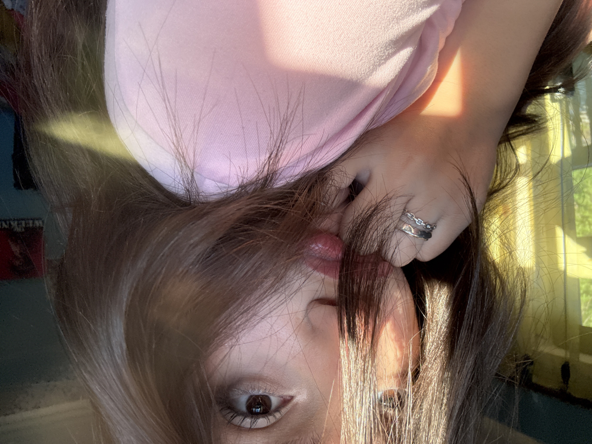 Person captures upside-down selfie indoors wearing pink top