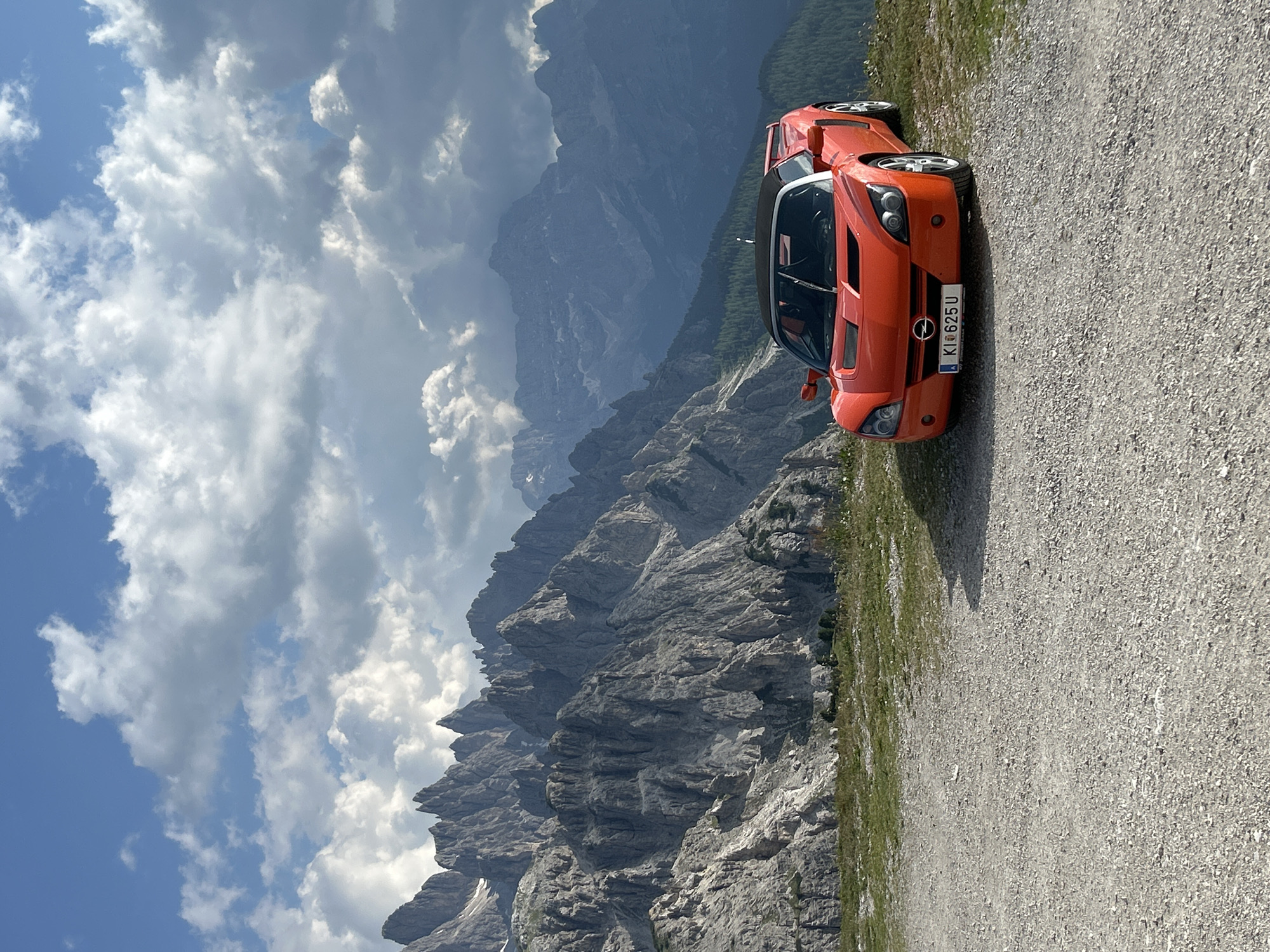 Orange Opel GT parked against sweeping mountain valley views