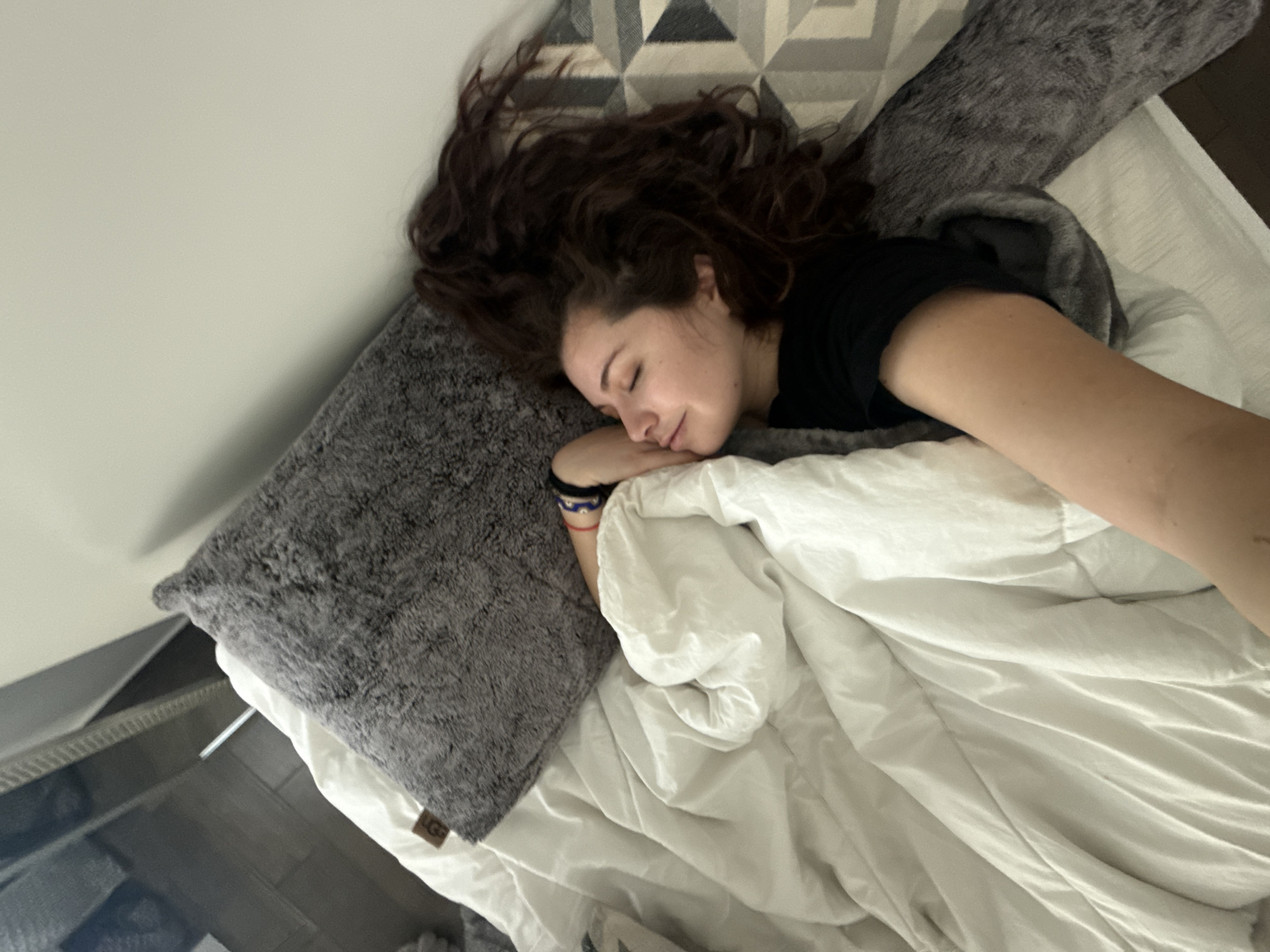 Woman rests in bed, makes peace sign gesture