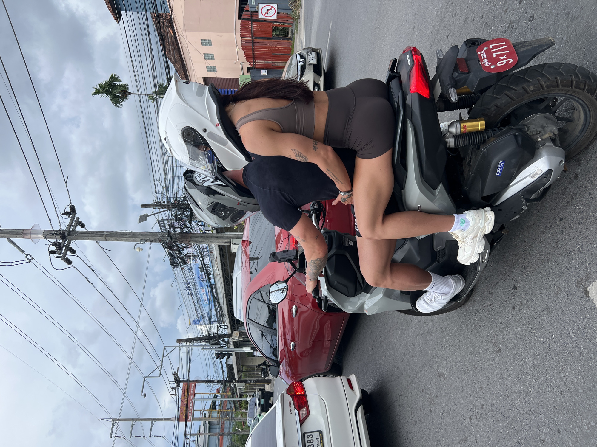 Scooters and motorcycles moving through Chalong streets on a cloudy morning