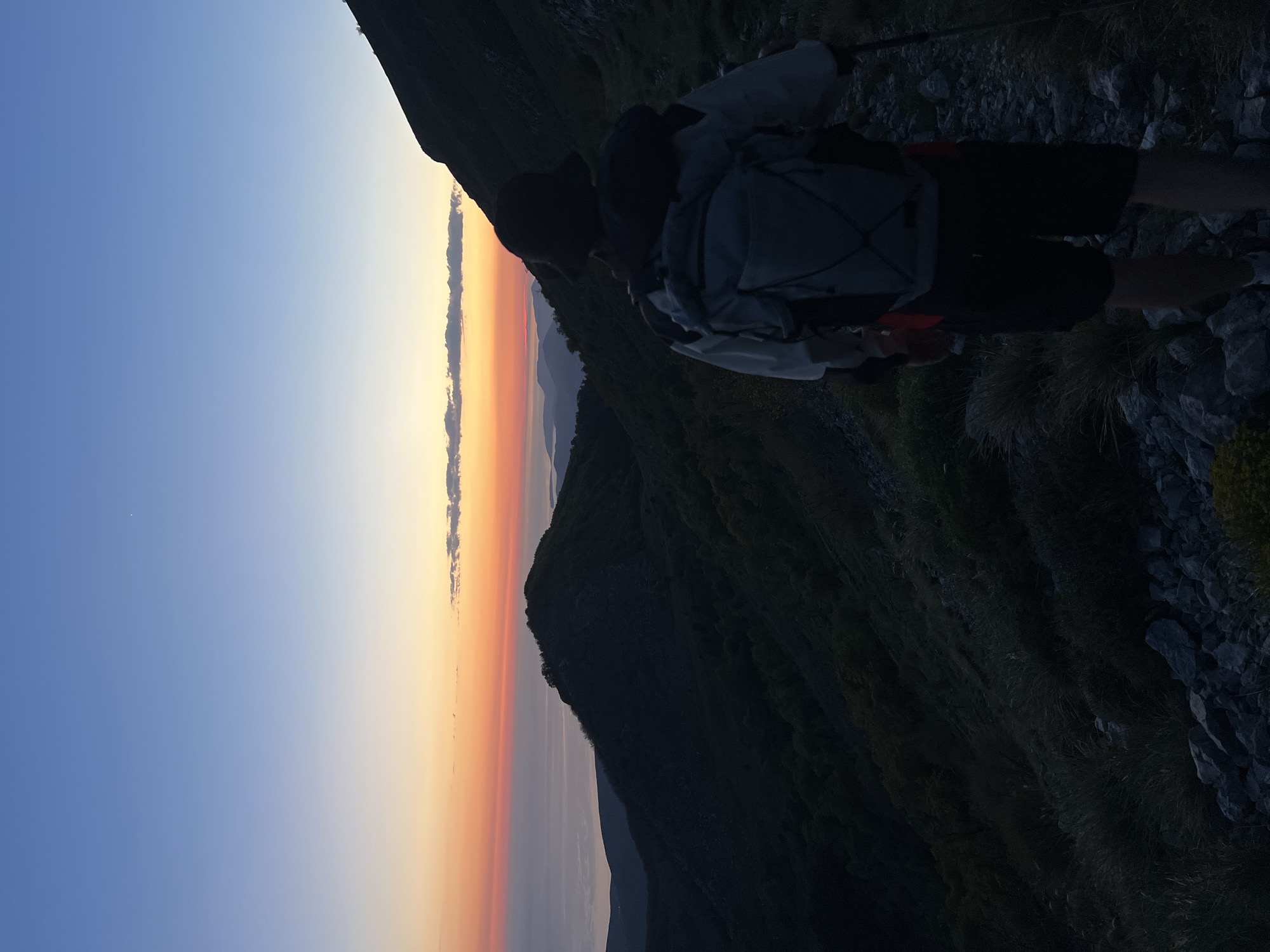Hiker watches sunset from mountain slope in Dolovi, Montenegro