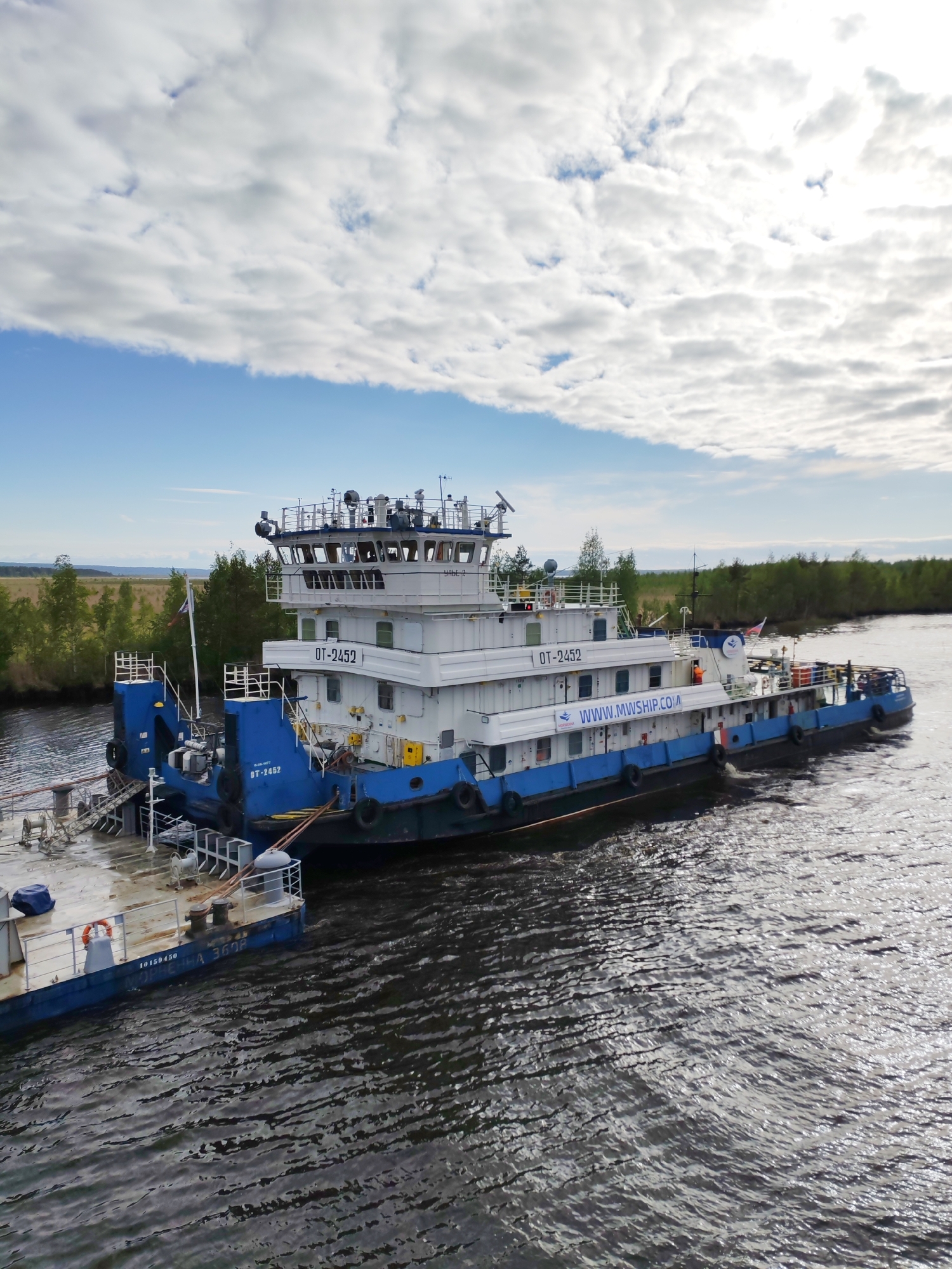 Tugboat pushes gravel barges along Russian river near Ozernoe Ust'e