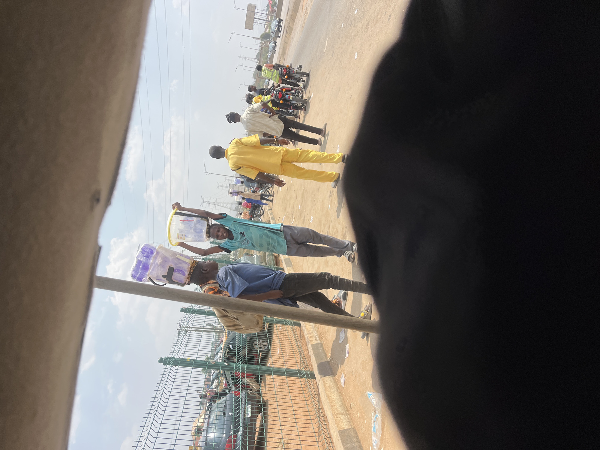 Street vendors carry goods along Nigerian village roads