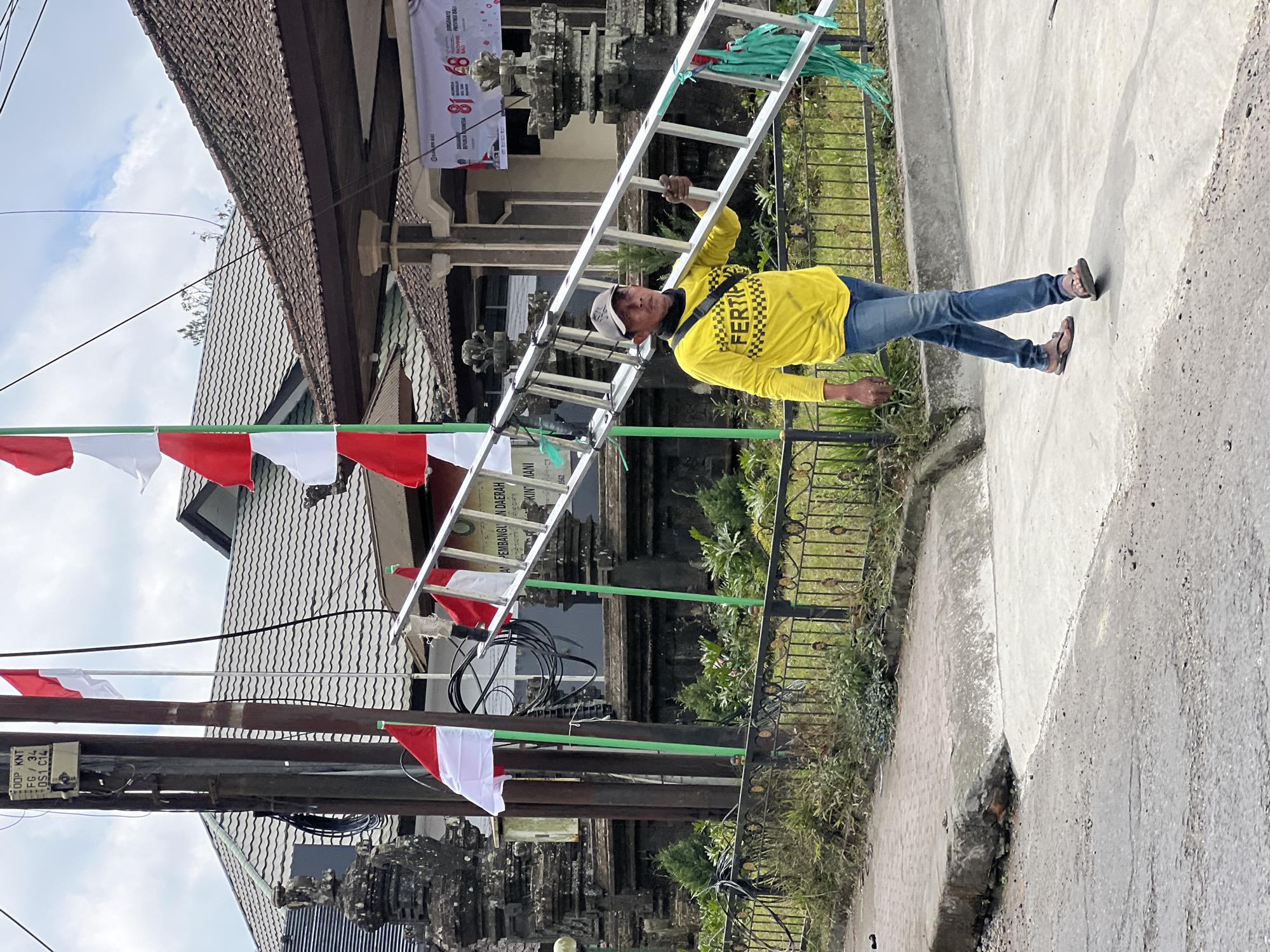 Hauling a metal ladder through Kintamani on a workday