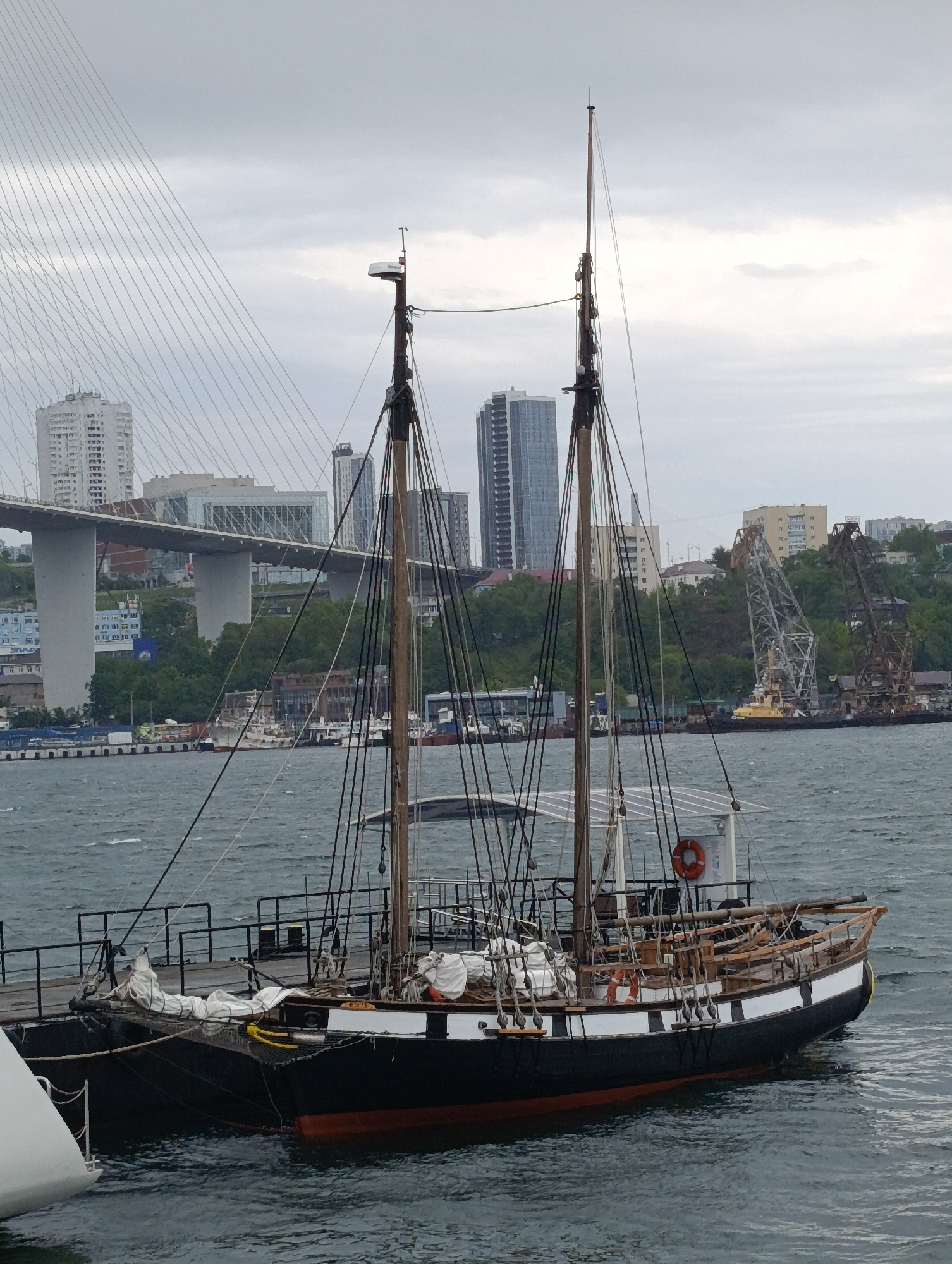 Traditional sailing vessel docked at pier under overcast skies
