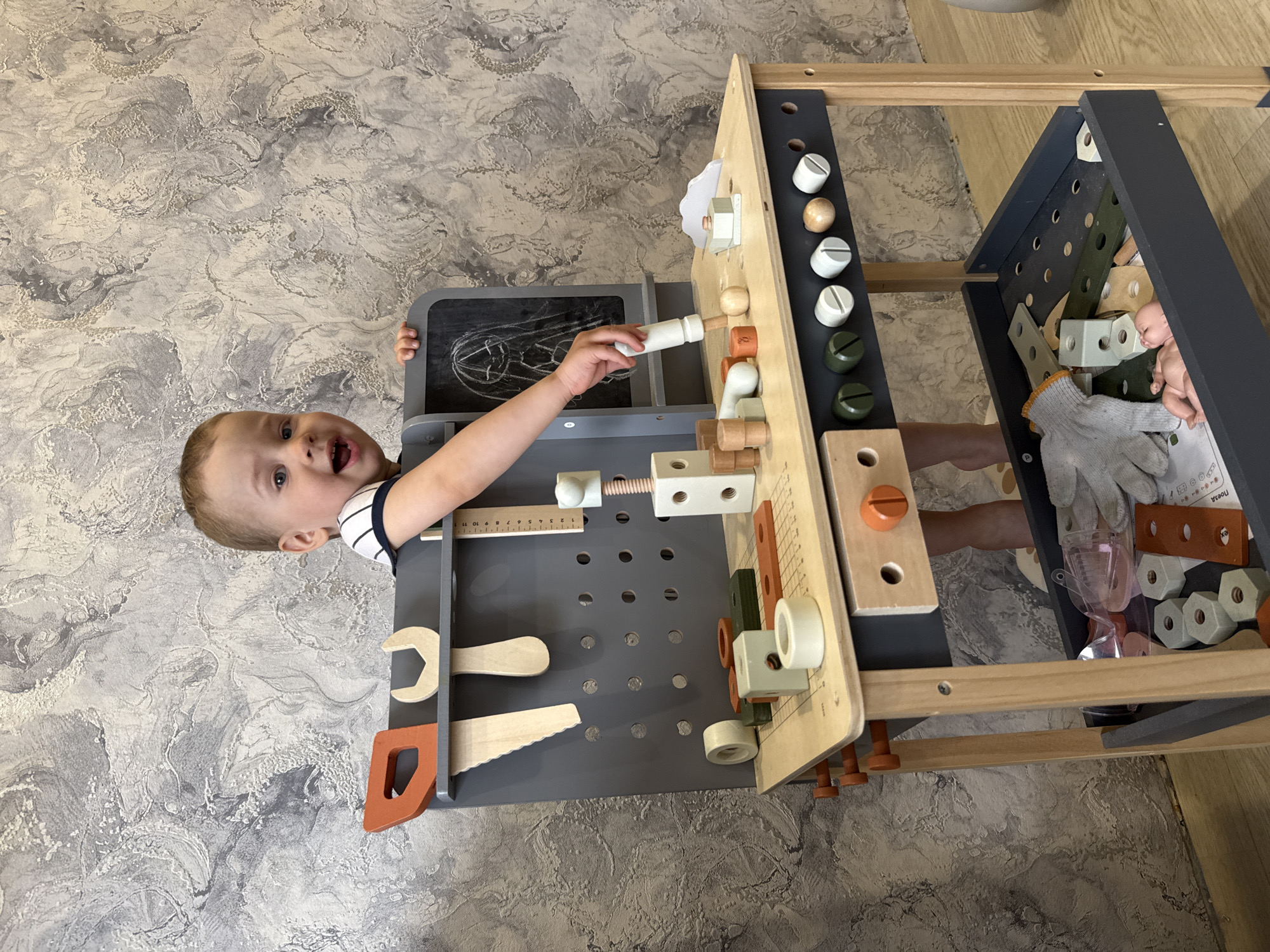 Toddler enjoys playful moments with wooden toy workbench indoors