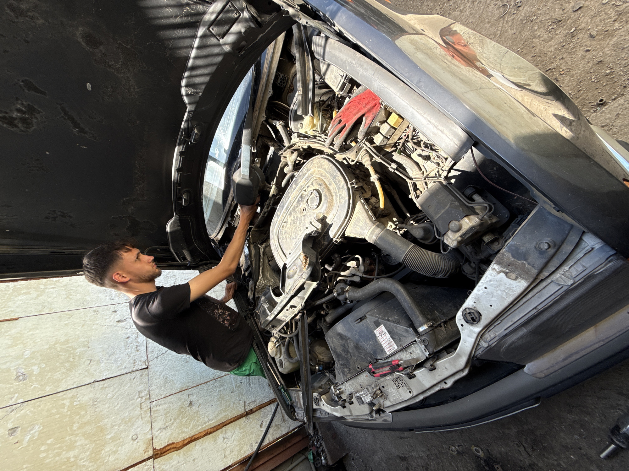 Mechanic works on engines in Bulgarian garage with cat