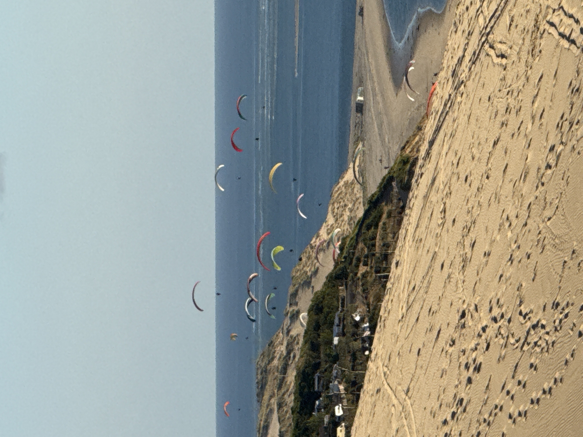 Evening visitors document Dune of Pilat's sandy slopes, paragliders
