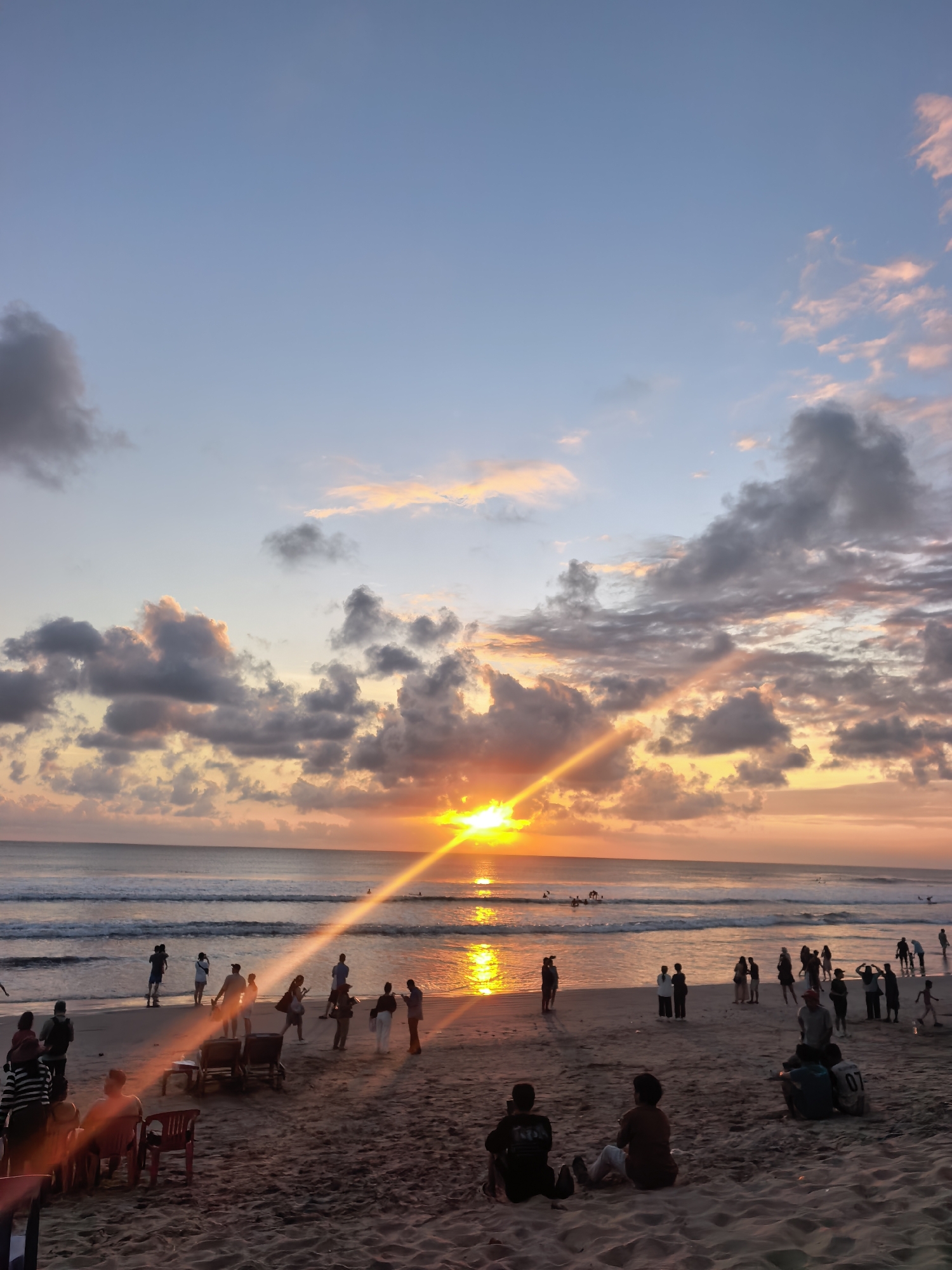 Kuta Beach crowds gather under a soft sunset sky