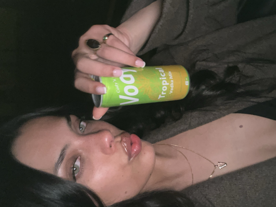 Woman poses with tropical vodka mix drink in Paris selfie