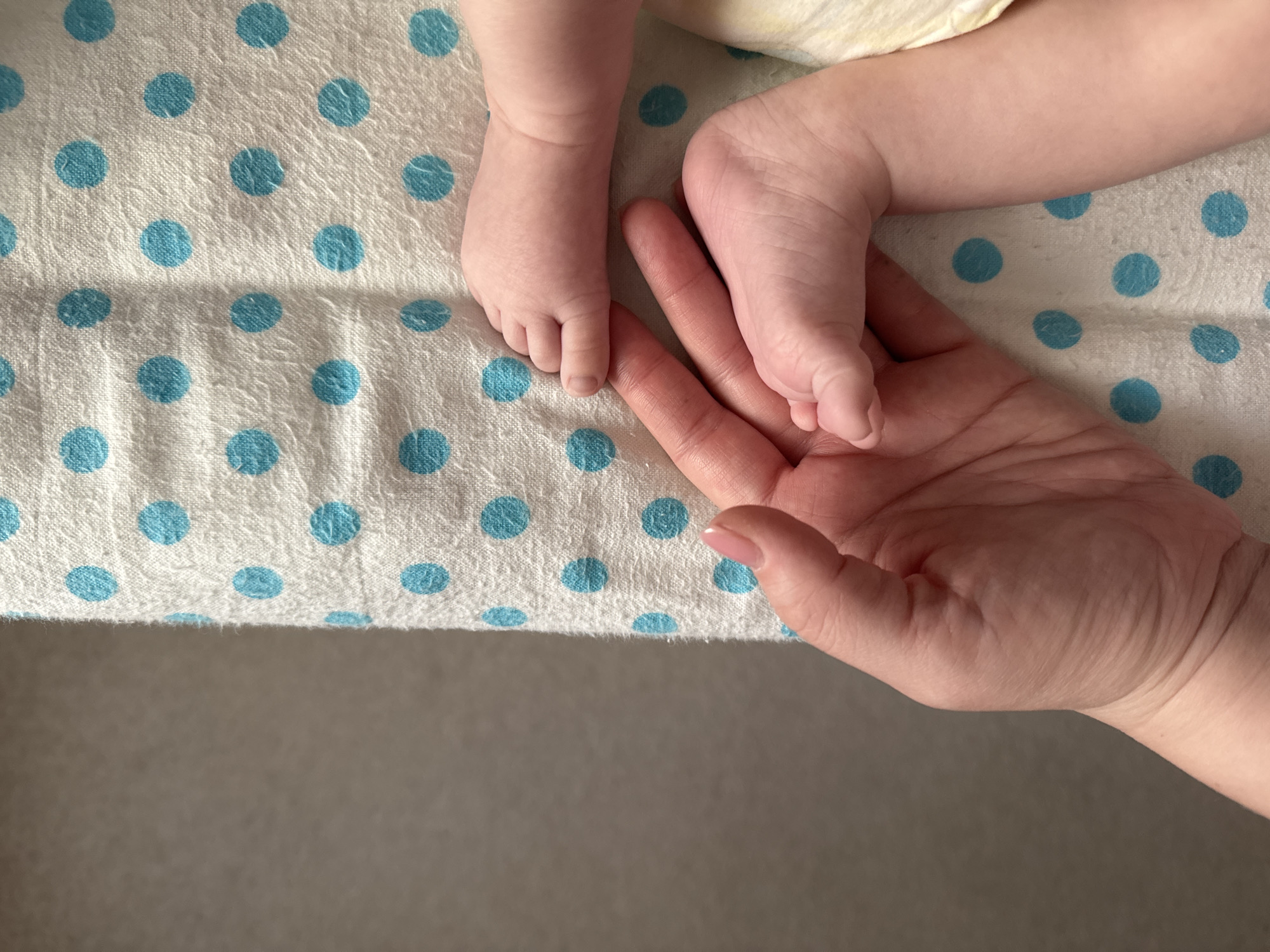 Adult tenderly holds baby's feet in gentle moment