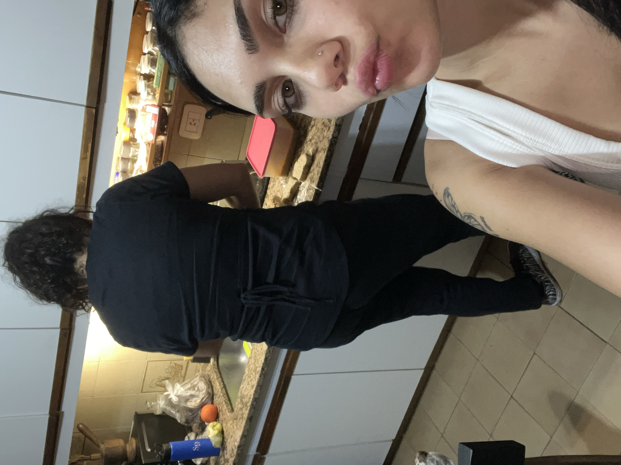 Woman takes kitchen selfie with person in background, Buenos Aires