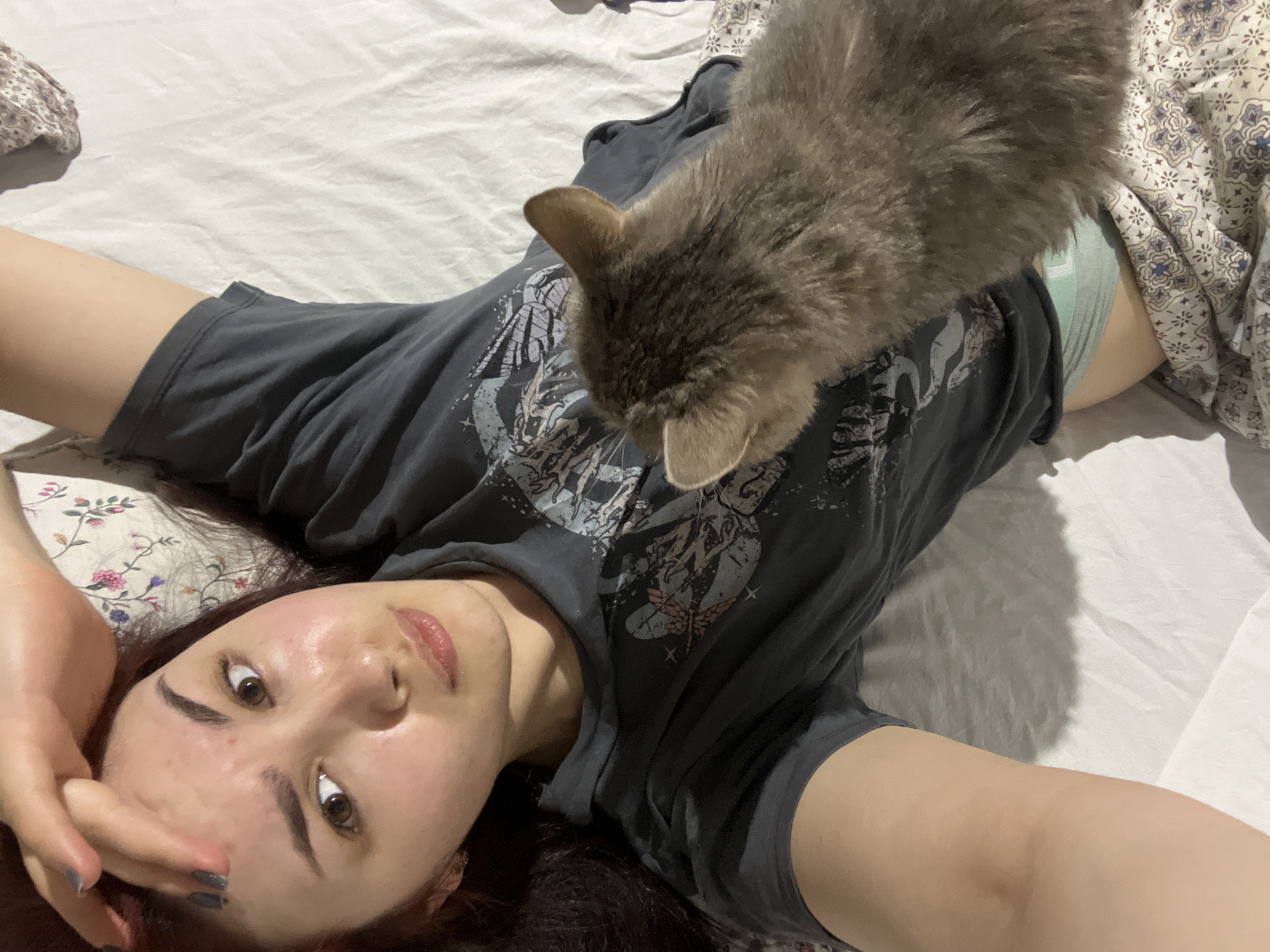 Woman poses with gray cat on bed in Neftekamsk