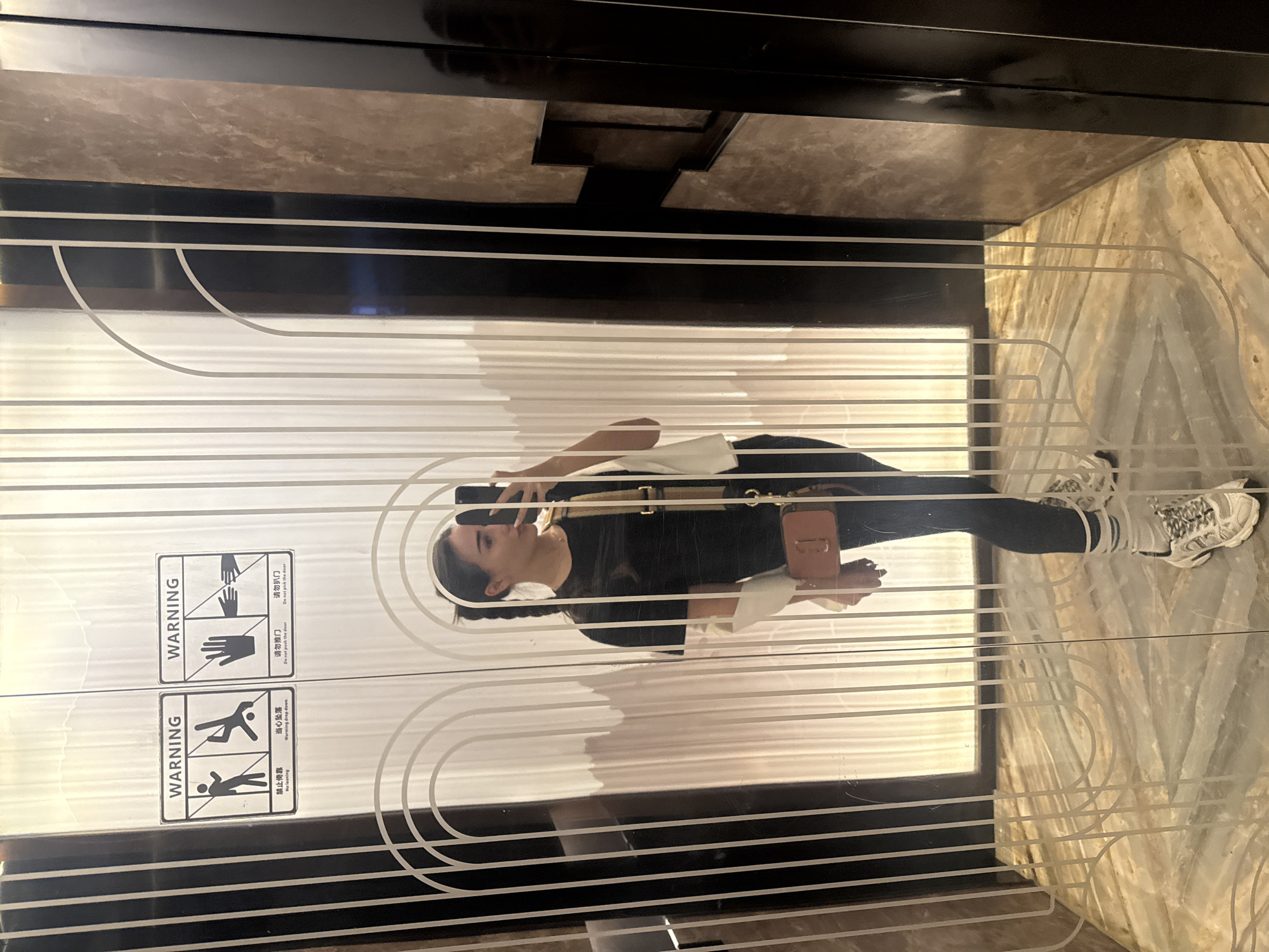 Woman takes selfie at warning-labeled doors in Yiwu