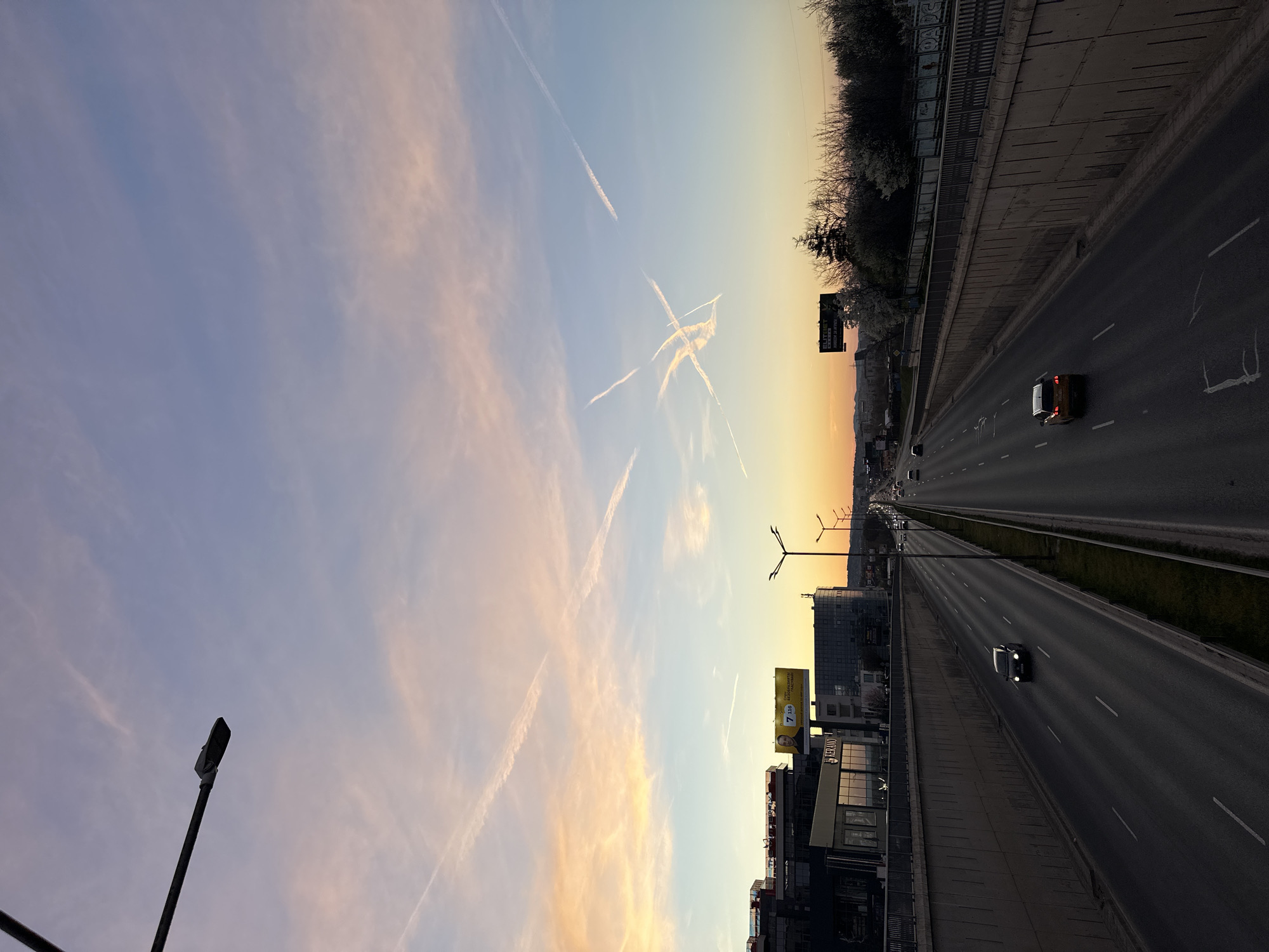 Evening traffic flows on Sofia highway under vapor-streaked sky