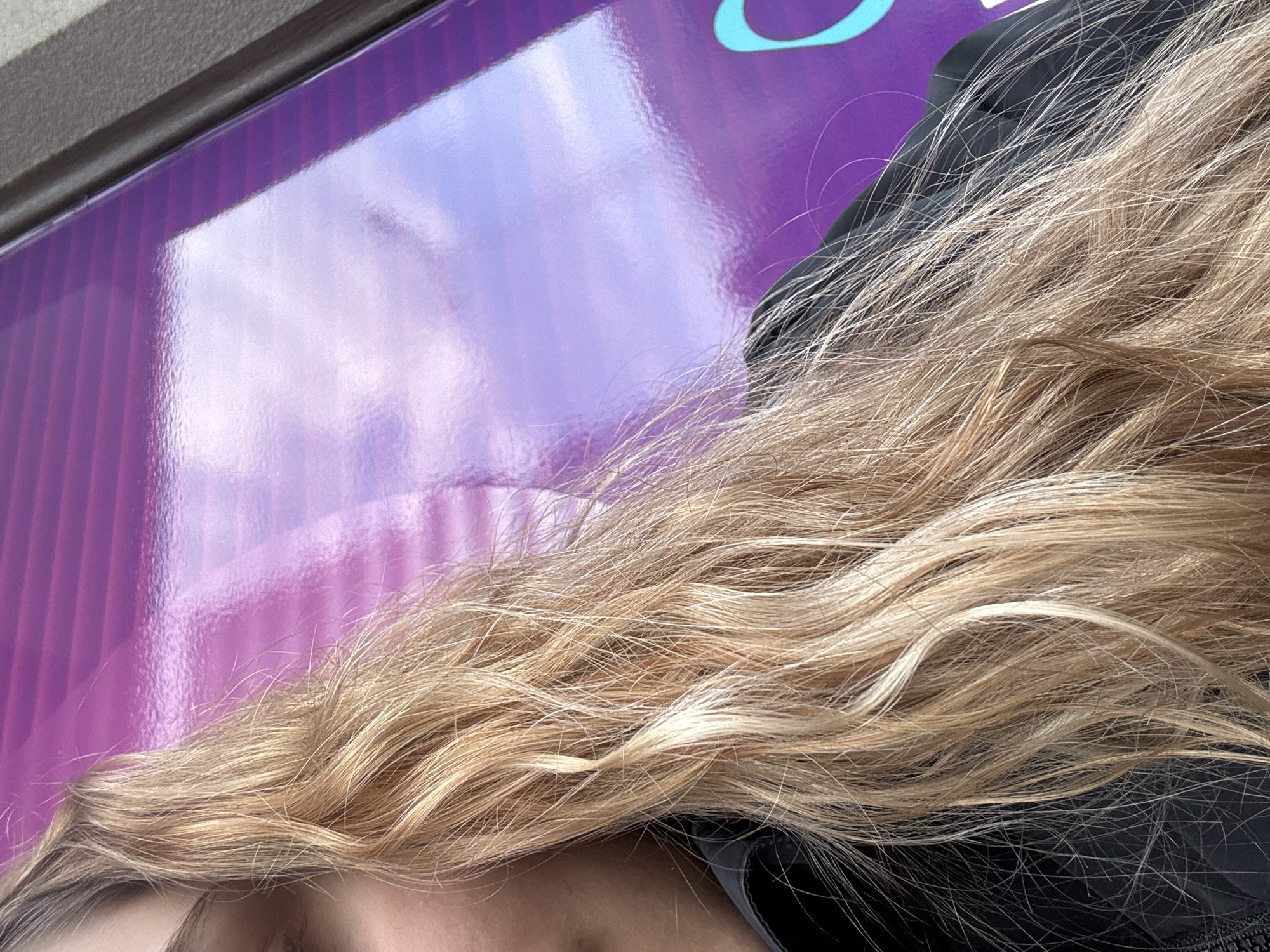 Person with blonde hair seen against purple reflective surface
