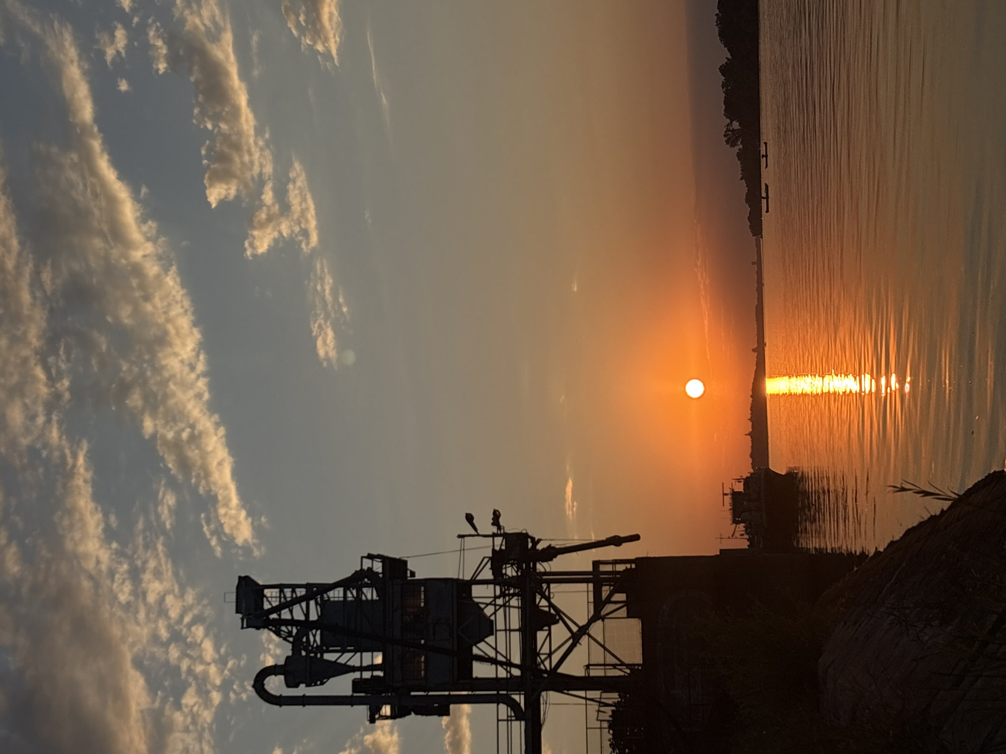 Sunset over Belgrade's riverfront, cranes and calm water