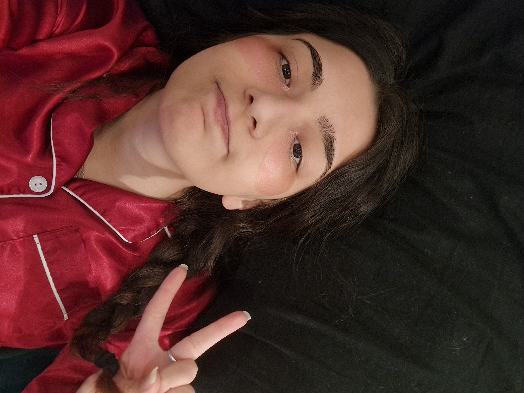 Woman in red pajamas makes peace sign indoors