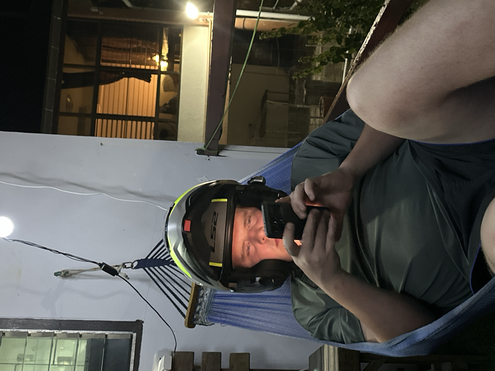 Hammock time in Karon, helmet on, phone in hand.