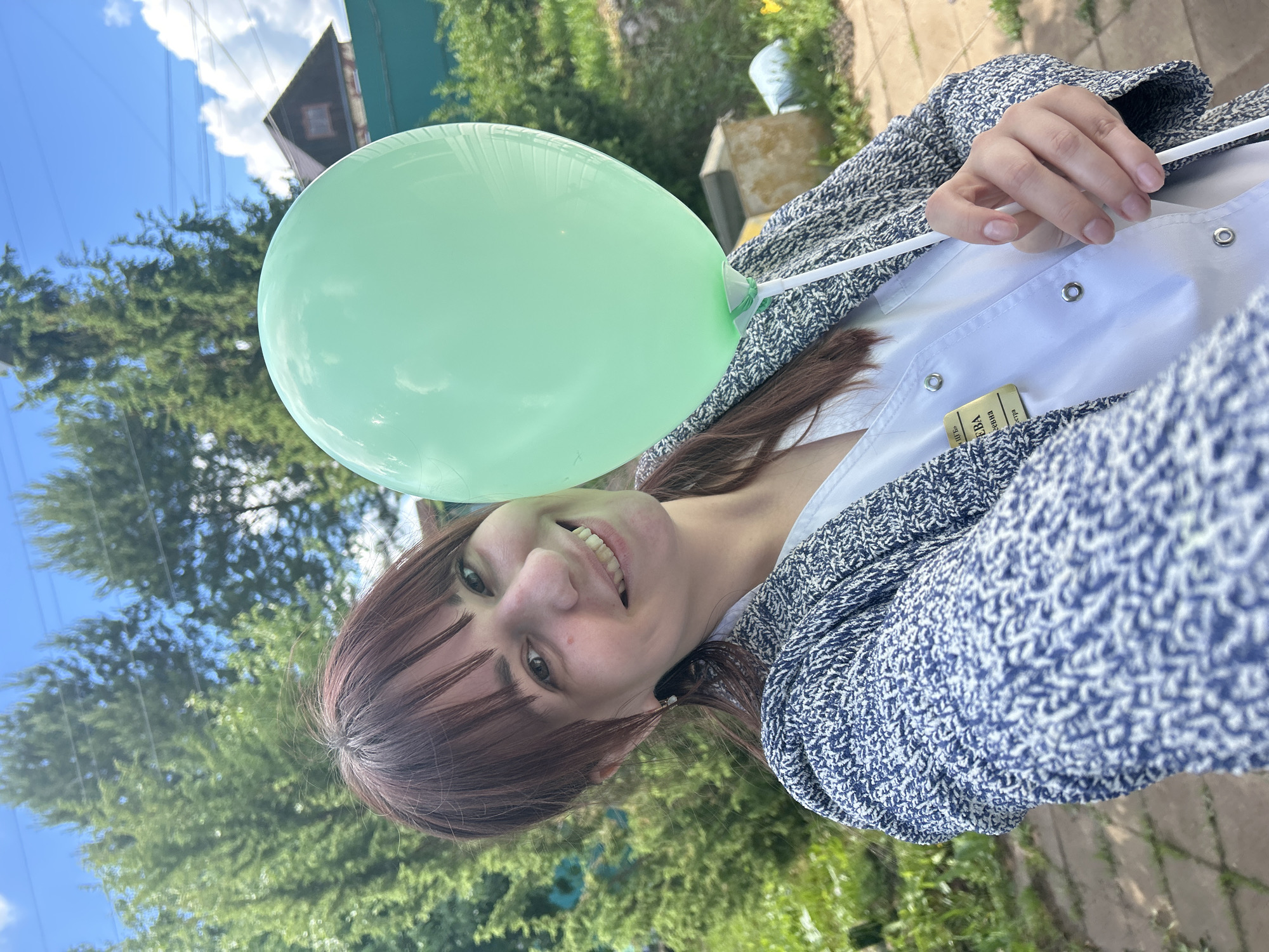 Woman holds green balloon outdoors in Russian town