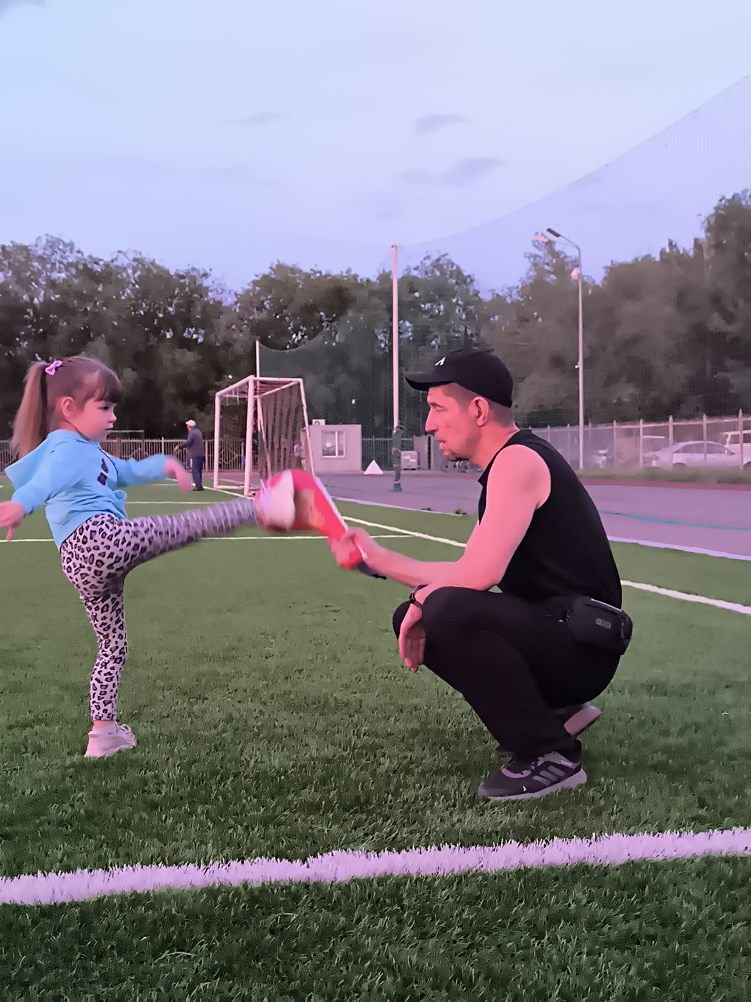 Martial arts drills at dusk on a Qarağandı sports field