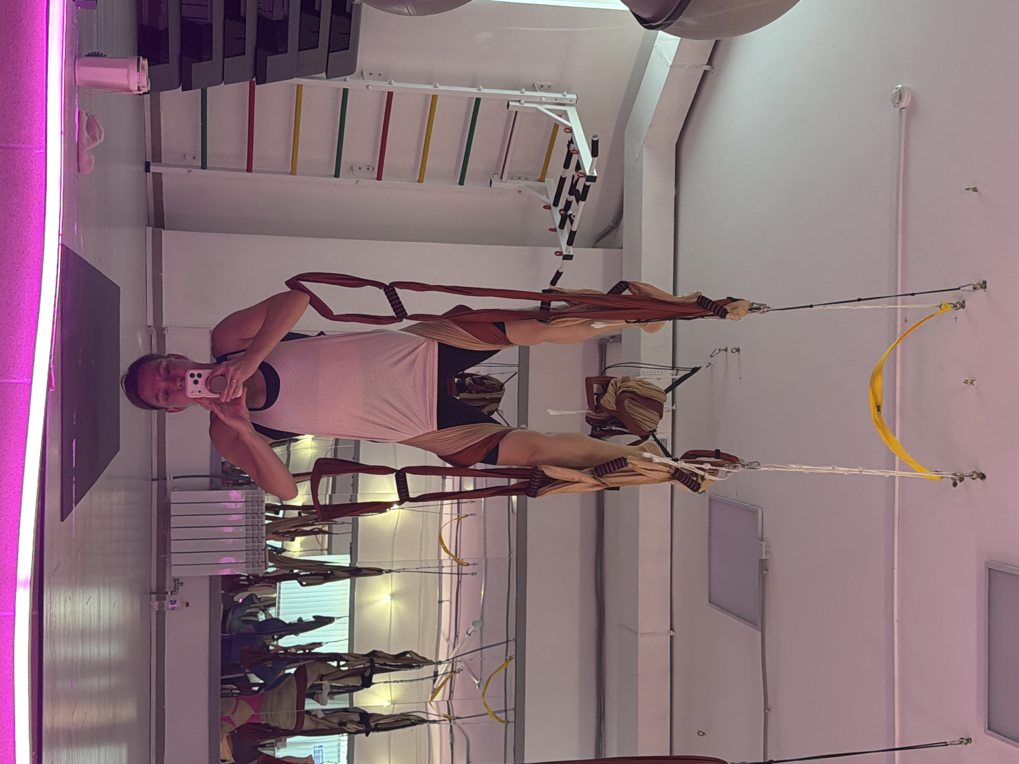 Aerial yoga session underway at a neon-lit Chaikovsky studio