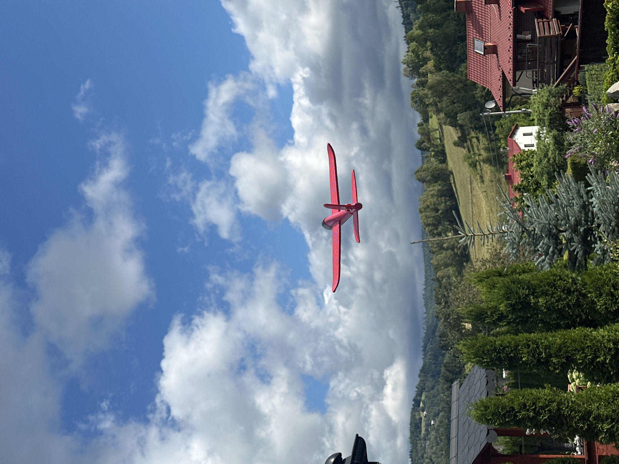 Red RC plane flying over forested hills in Wisła, Poland