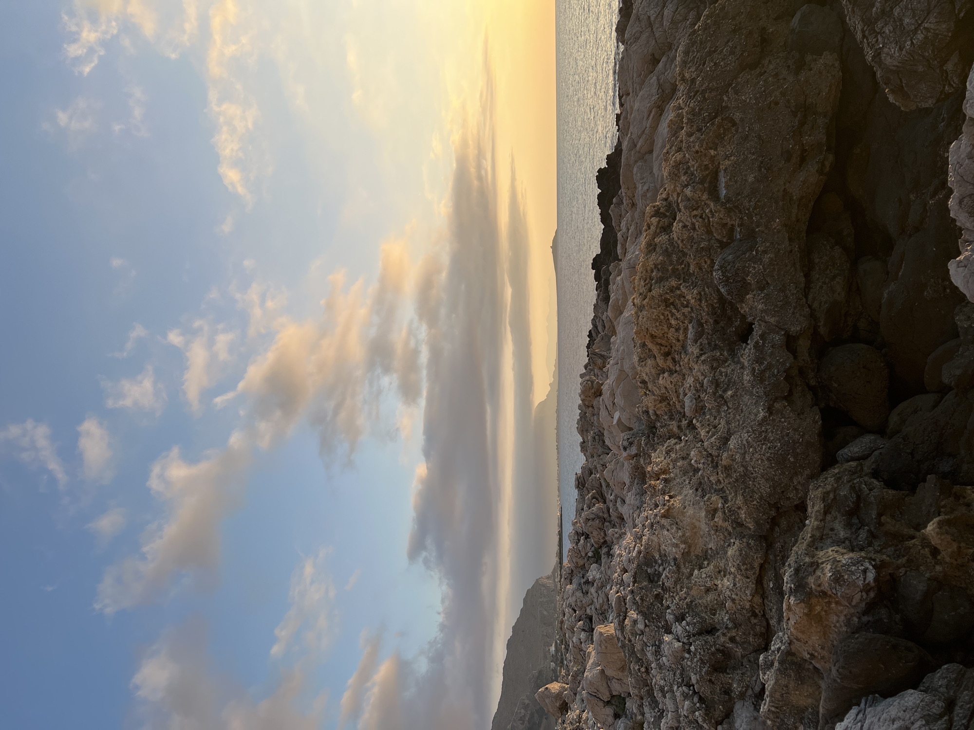 Sunset from Palermo's rocky Mediterranean coastline, crescent moon rising