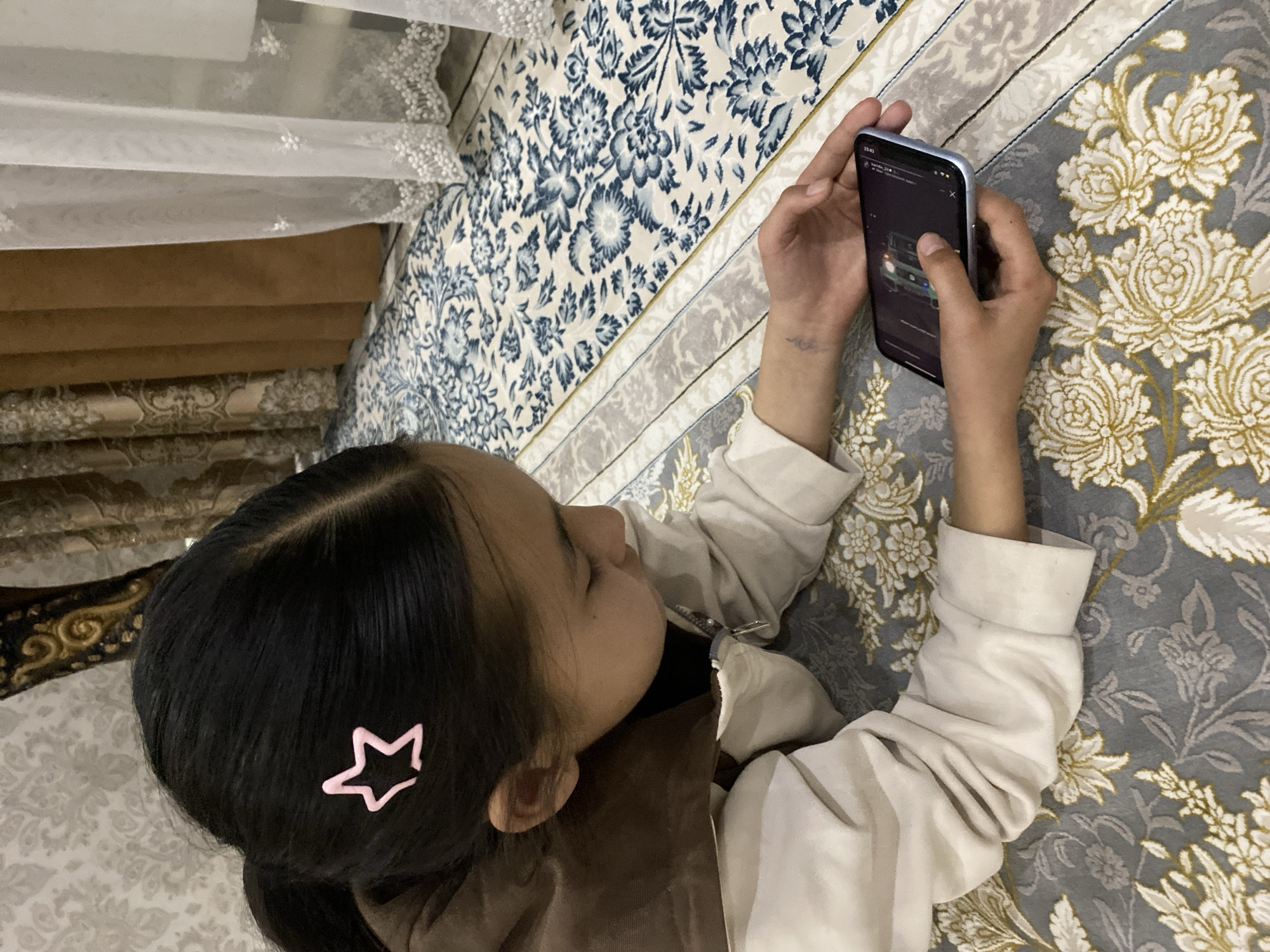 Girl with star hair clip views car on phone
