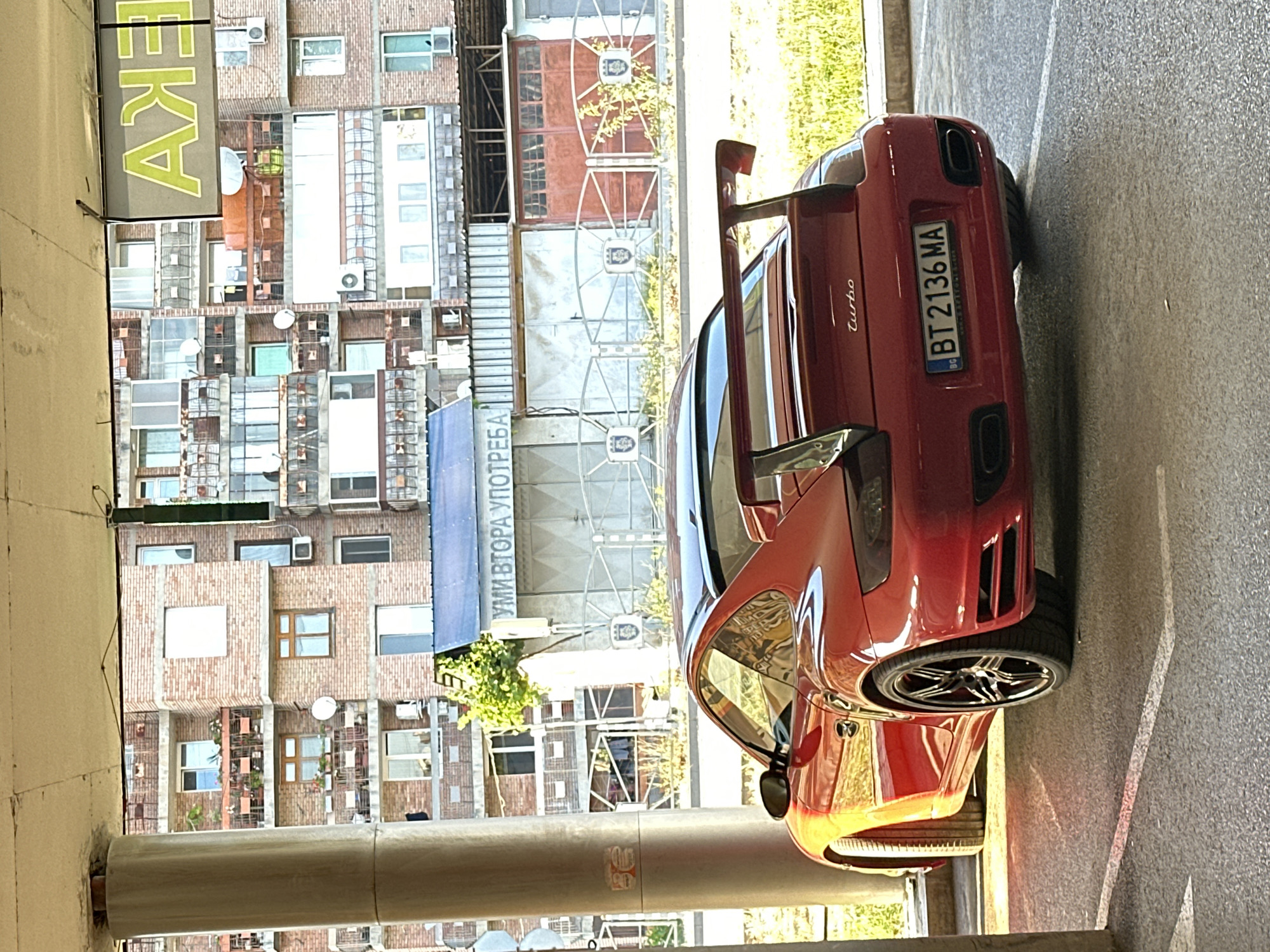 Red Porsche 911 Turbo parked under concrete cover in Veliko Tarnovo