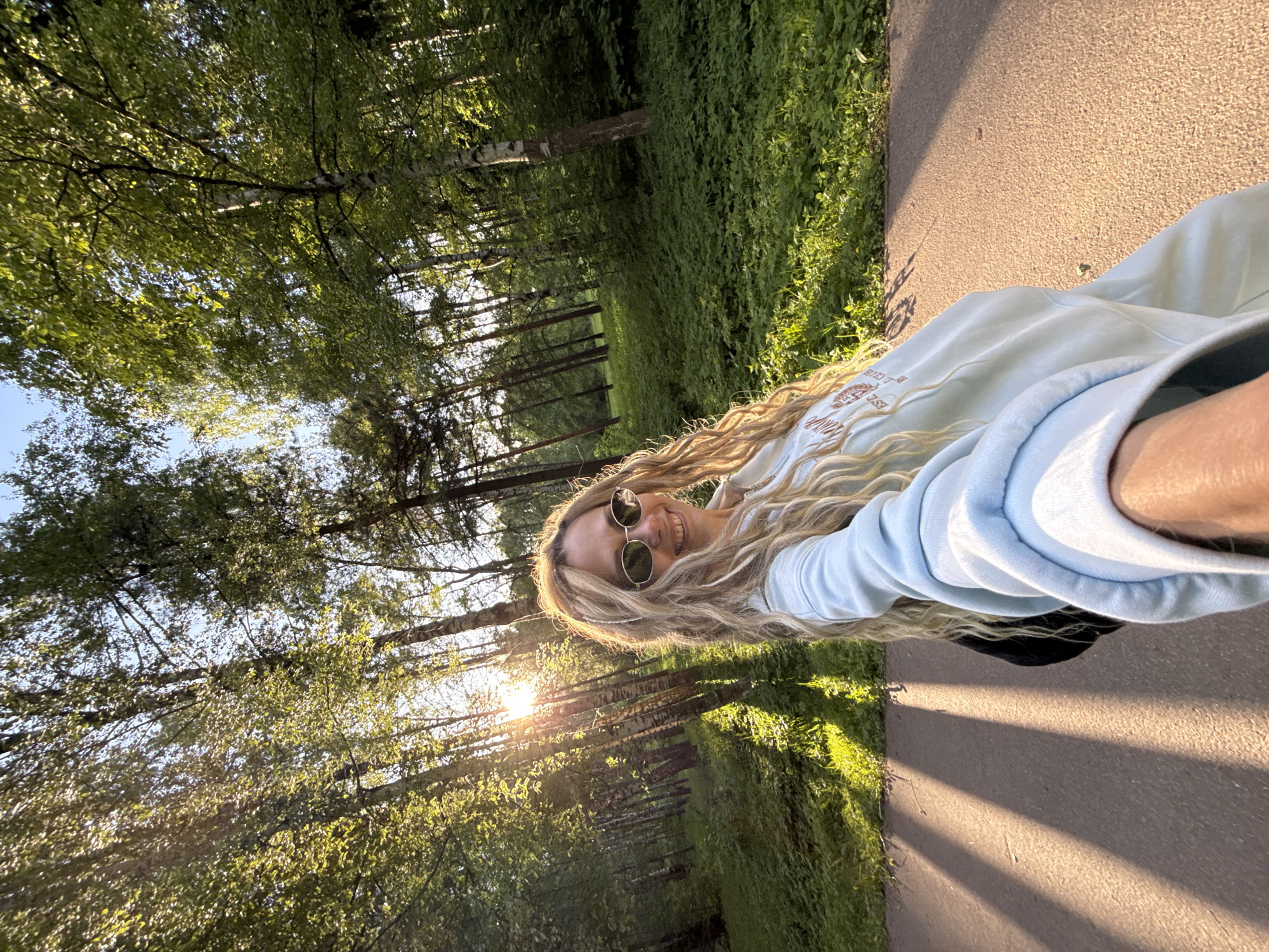 Woman takes selfie on sunny park path in Russia