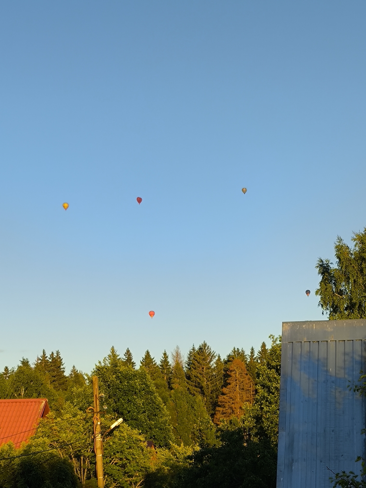 Hot air balloons fill the sky over a Russian village garden