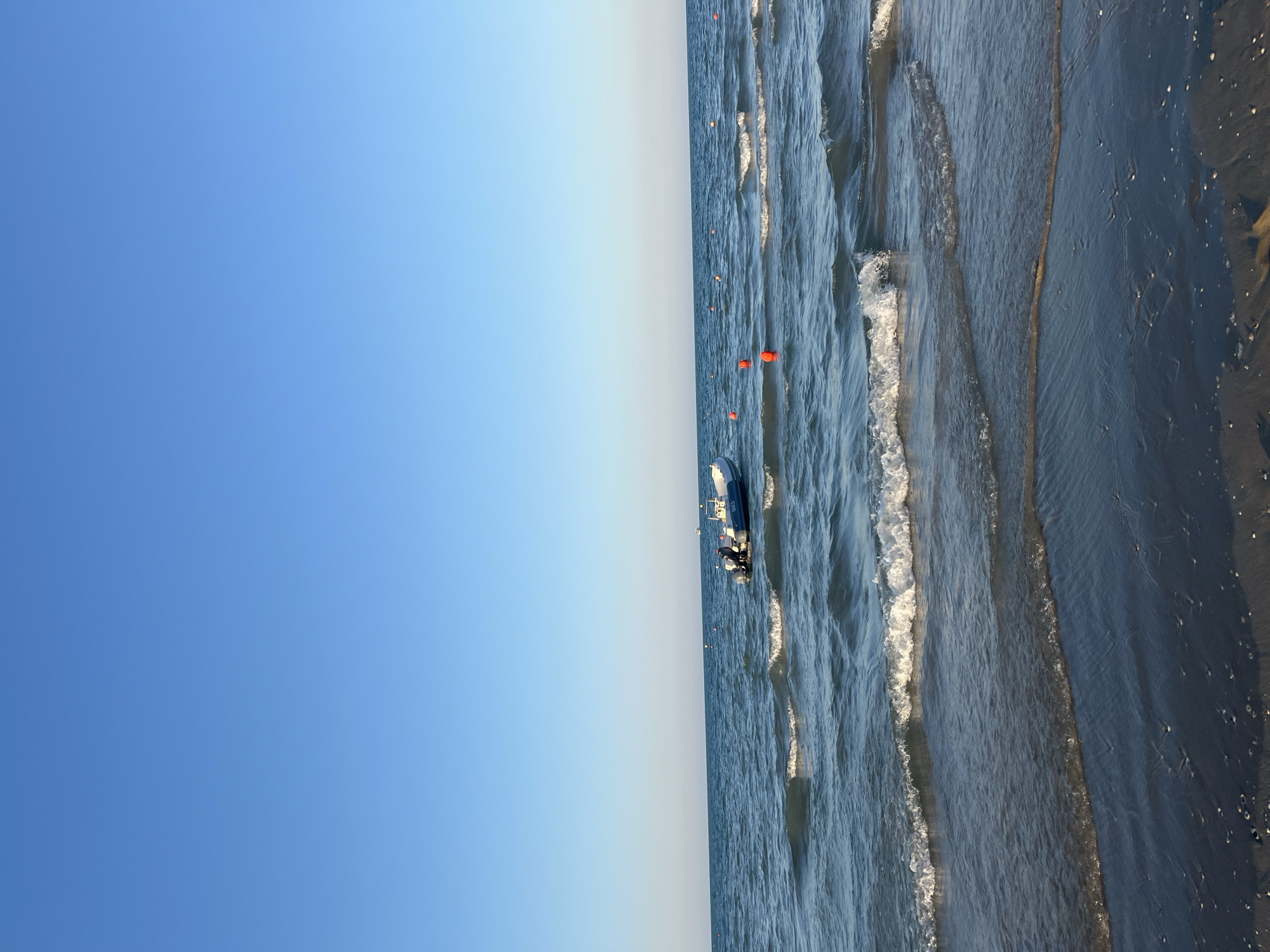Calm afternoon on Rimini beach, inflatable boat among orange buoys