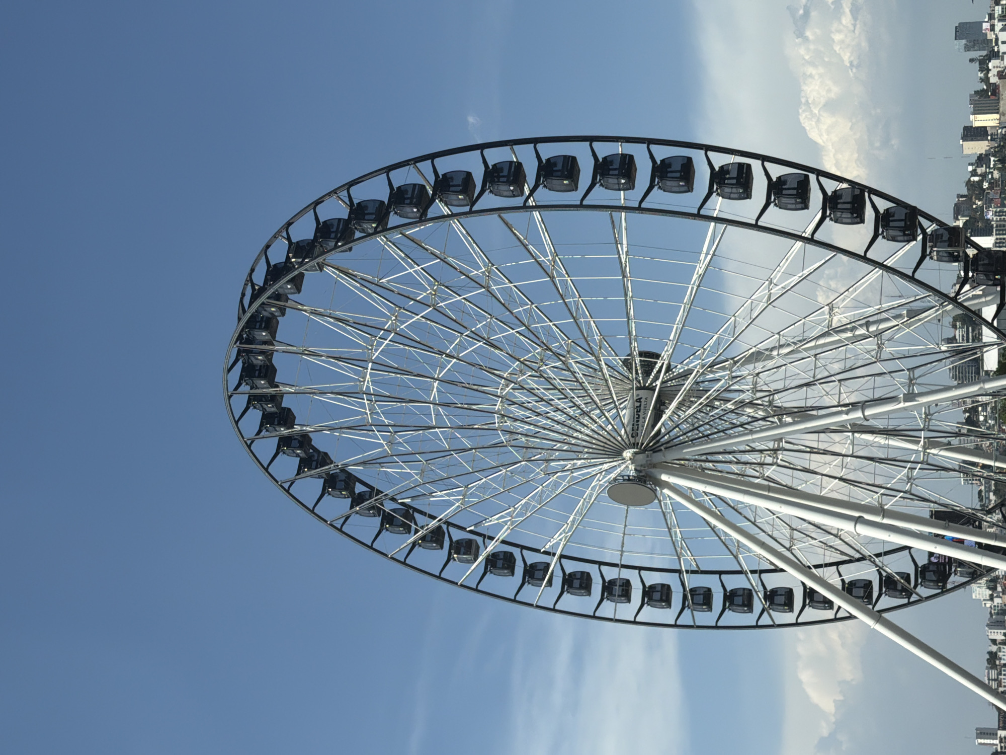 Ferris wheel spotted against blue sky, rotated image captured