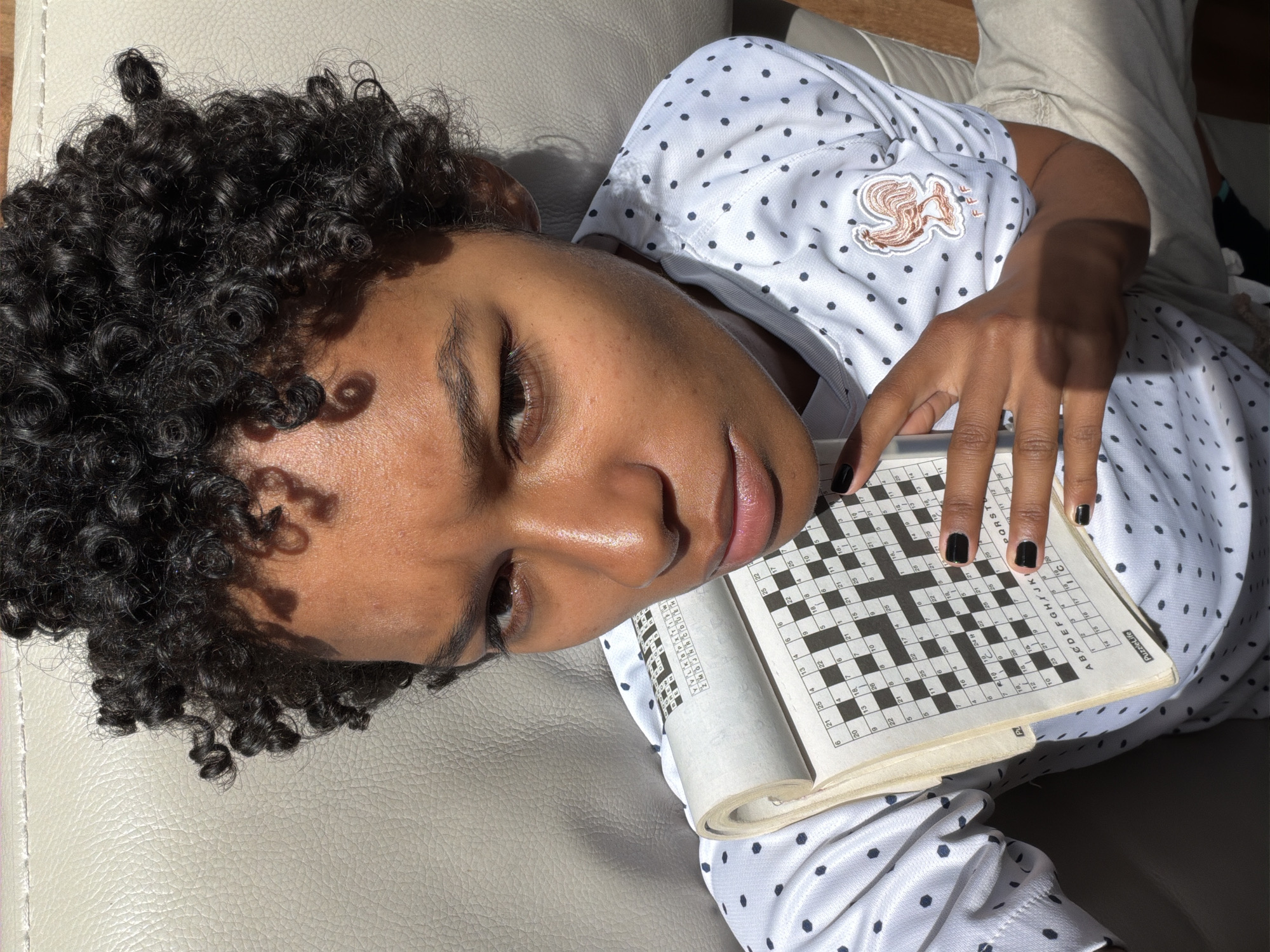 Person solves crossword puzzle on sofa in Champs-sur-Marne