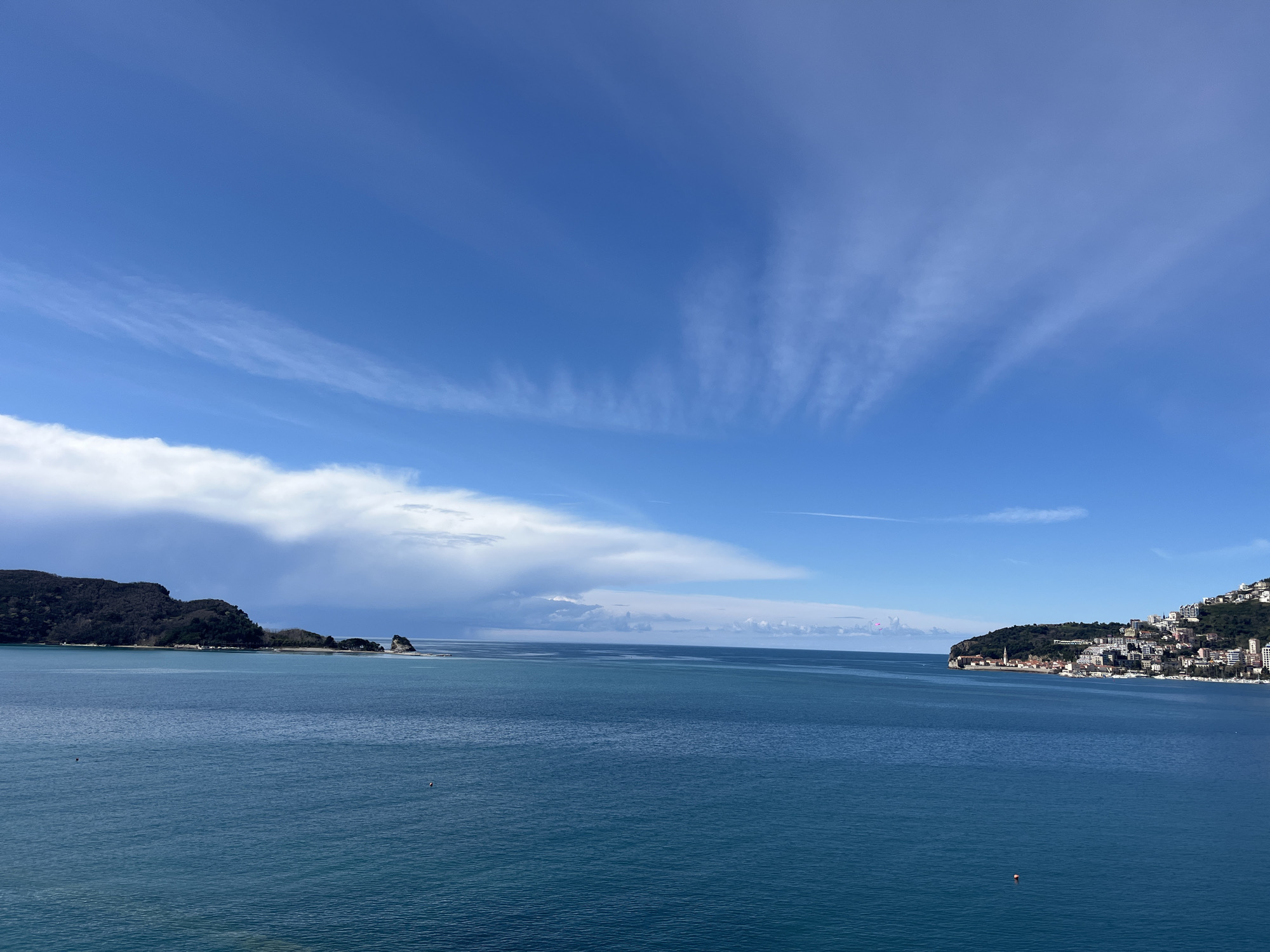 Tourist photographs Budva coastline from clifftop overlooks