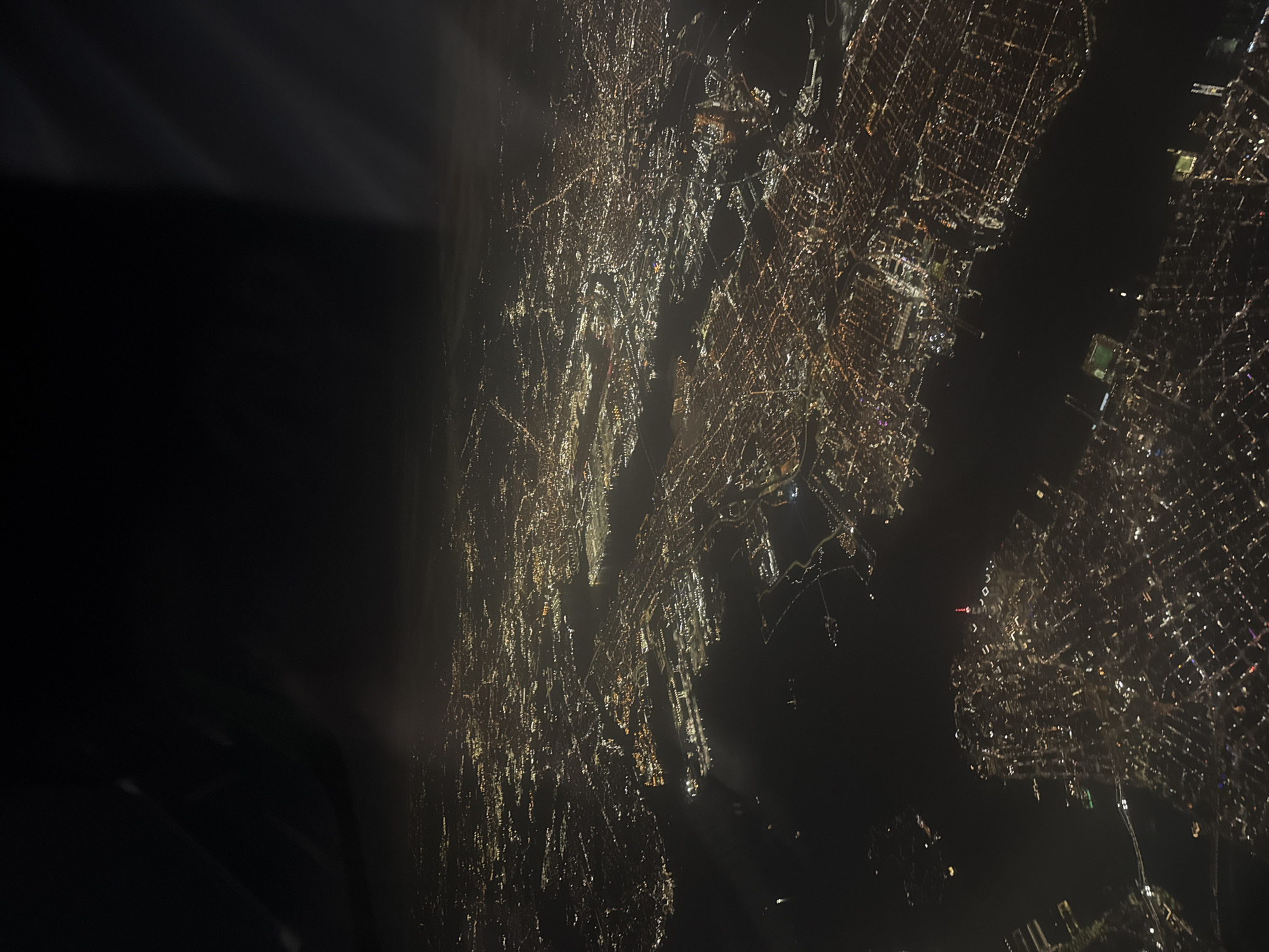 Nighttime aerial view captures illuminated city grid from aircraft