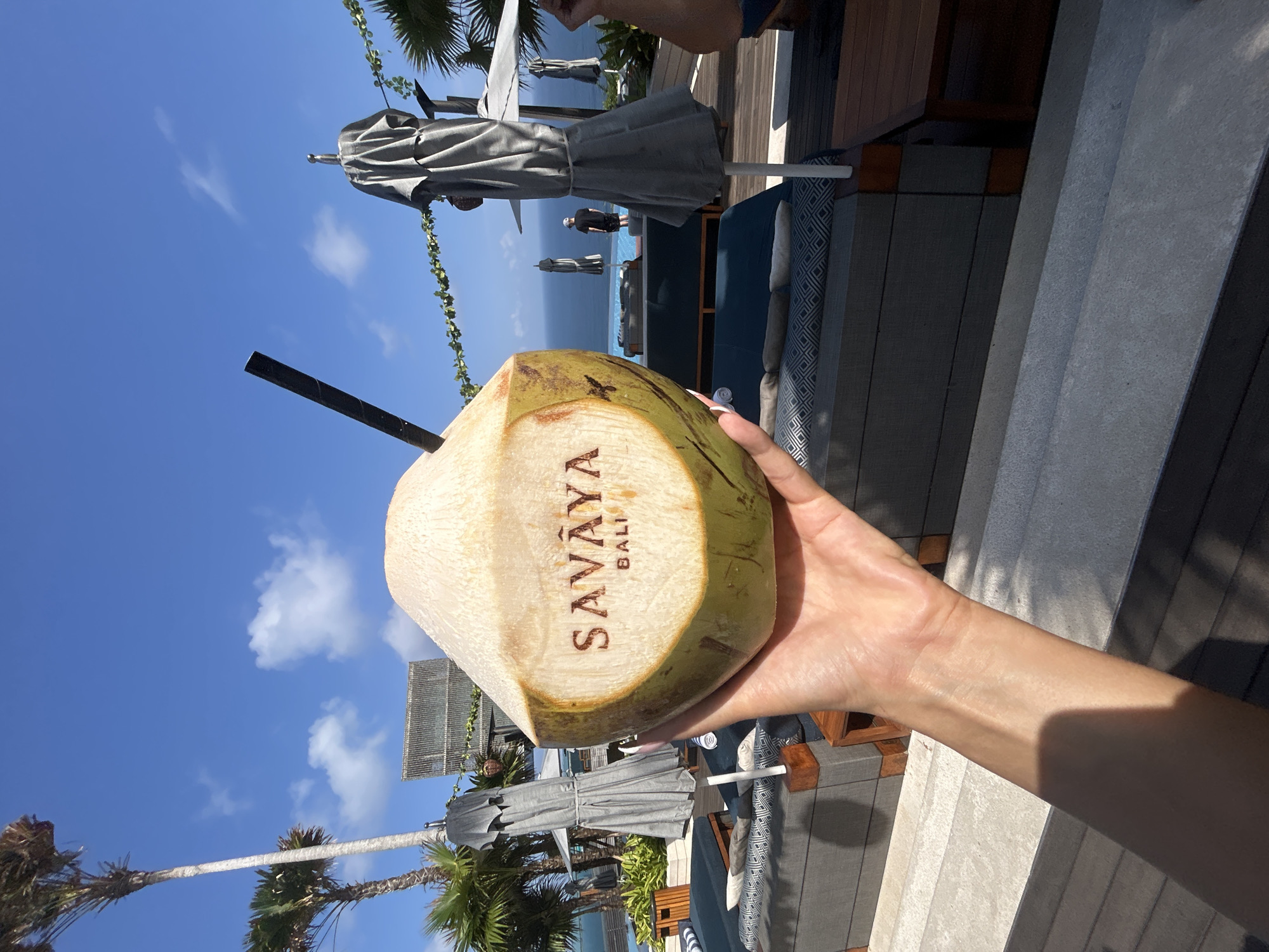 Savāya Bali resort vibes — poolside coconut and lawn sculptures