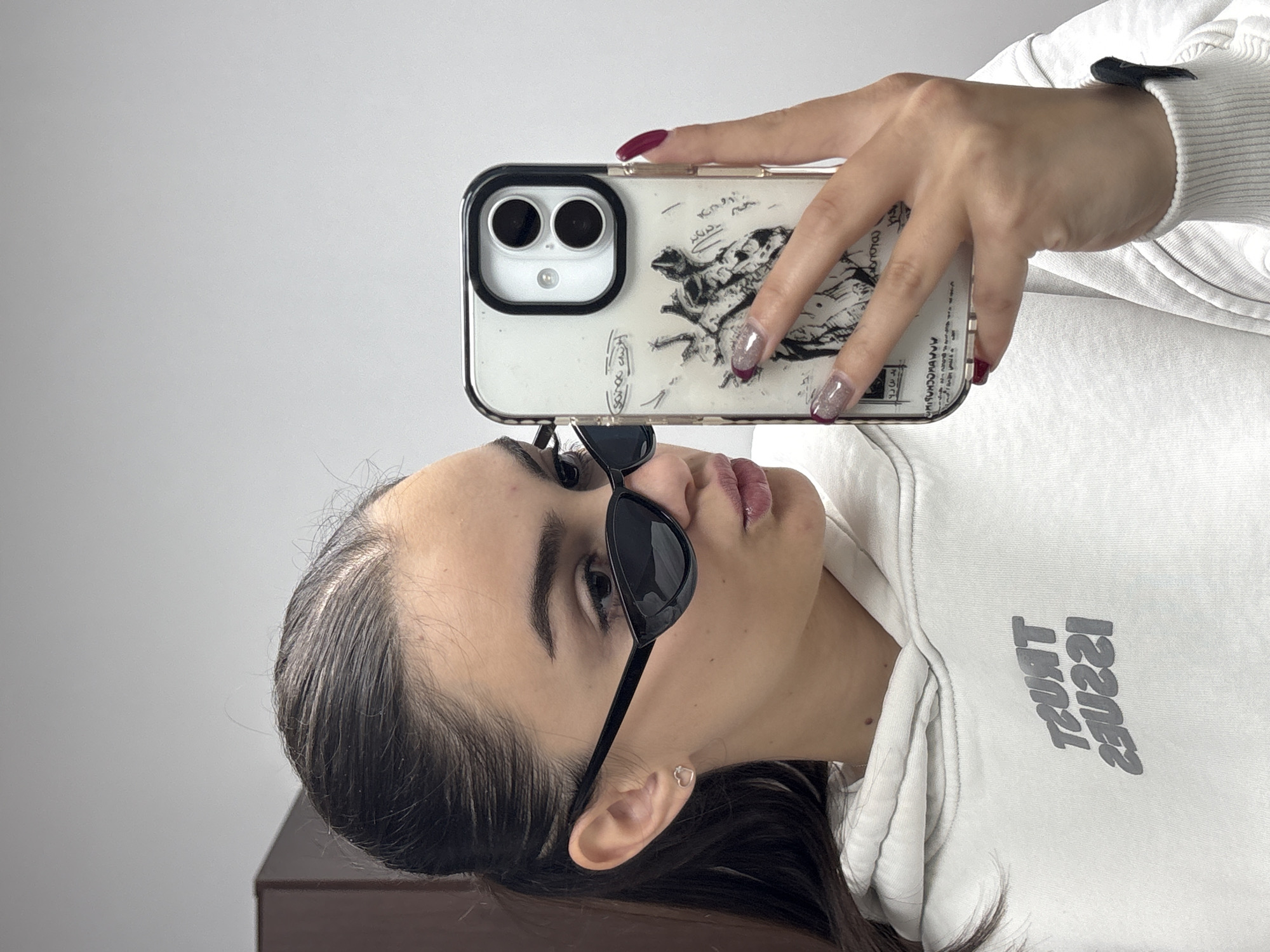 Woman takes selfie in white hoodie and sunglasses
