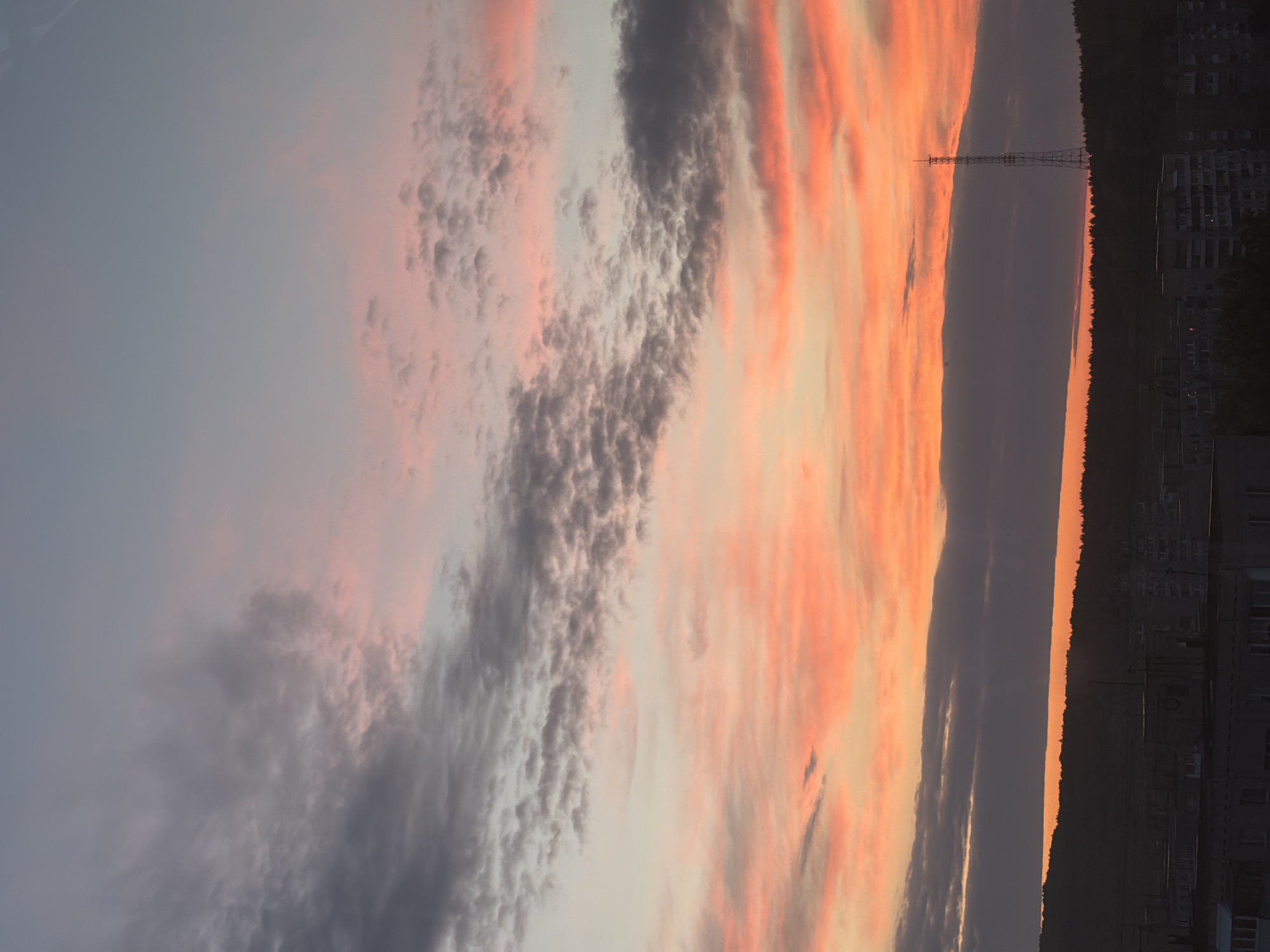 Dramatic sunset illuminates city skyline as witnesses document evening