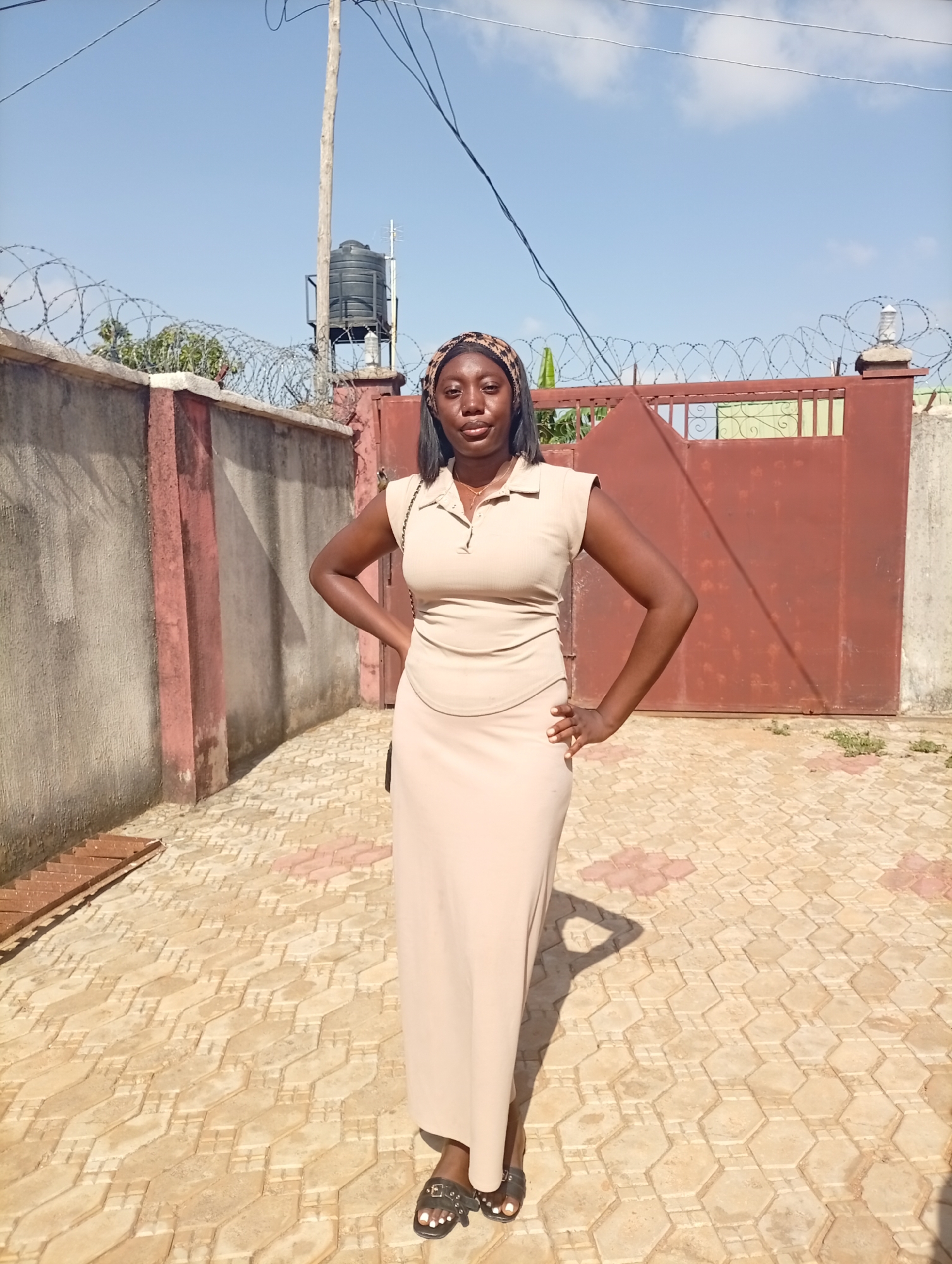 Woman in brown dress photographed near barbed wire barrier