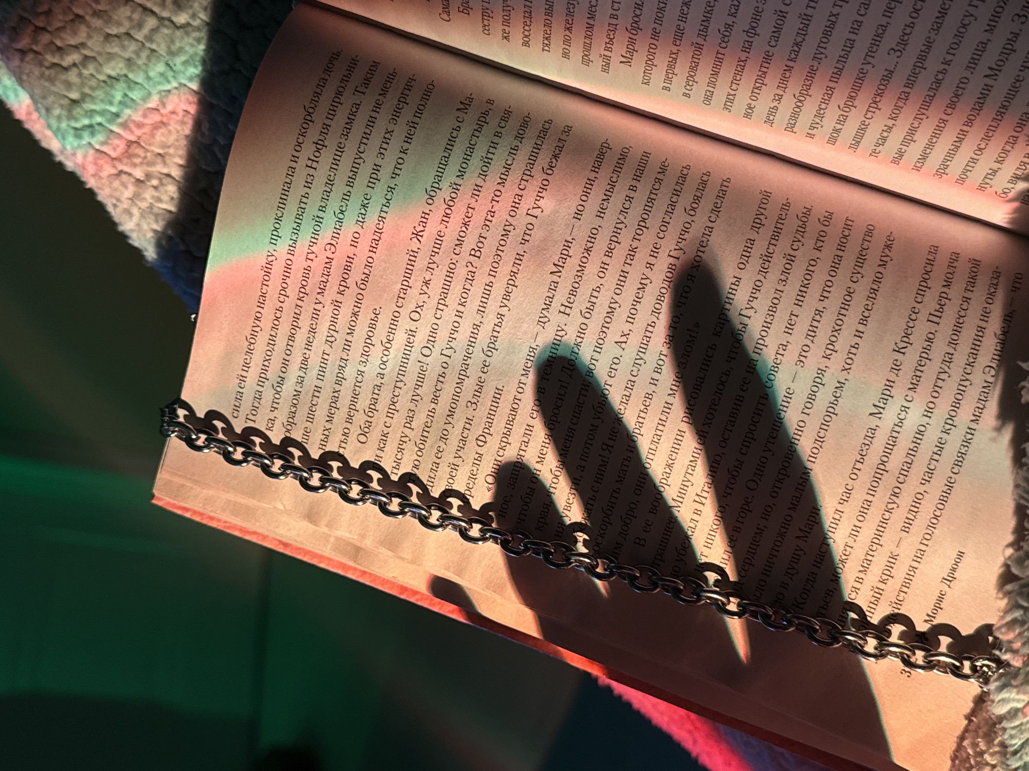Person reads Russian book while arranging jewelry in bedroom